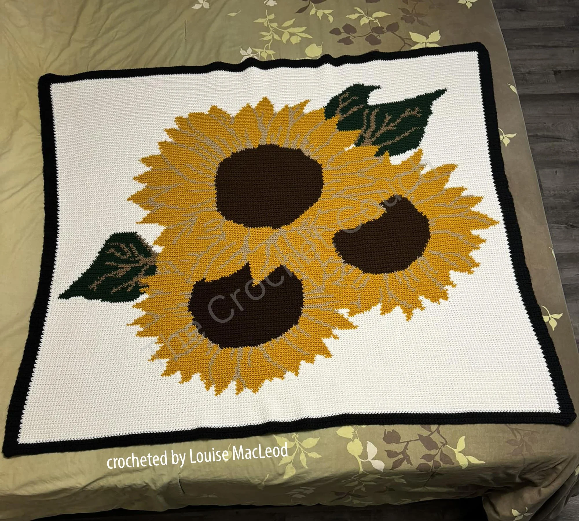 Crochet afghan featuring three large sunflowers on a white background with green leaves.