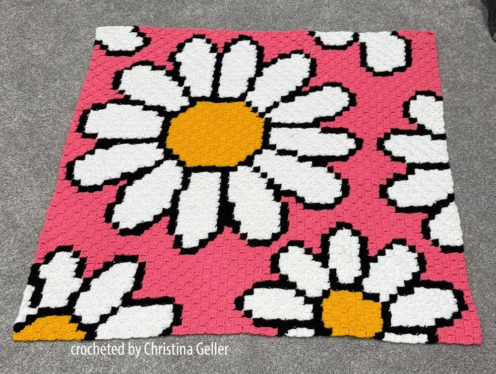 Bright and cheerful corner-to-corner baby blanket with large white daisies and golden centers
