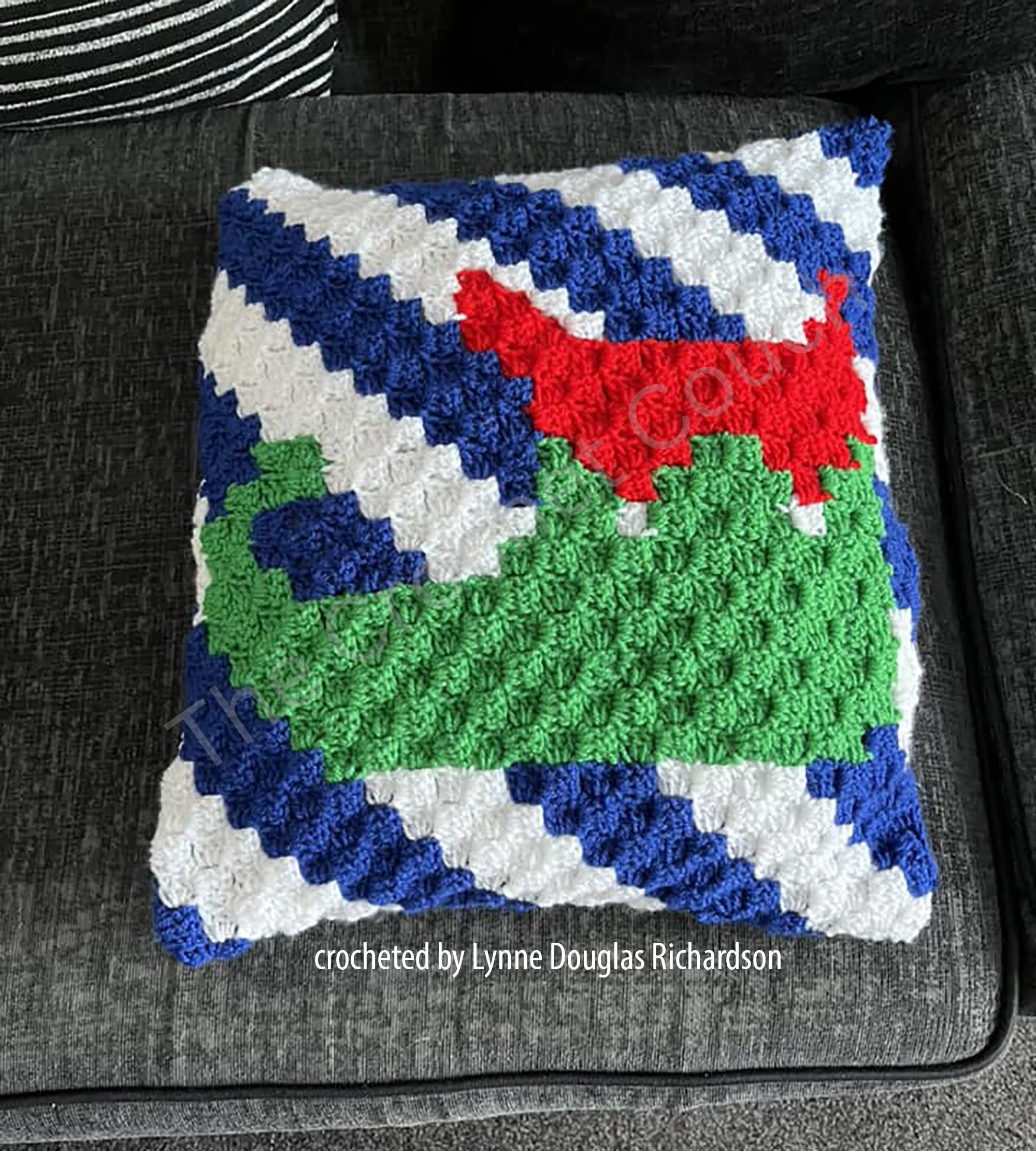 Crocheted pillow with blue and white stripes and an elf boot in red and green