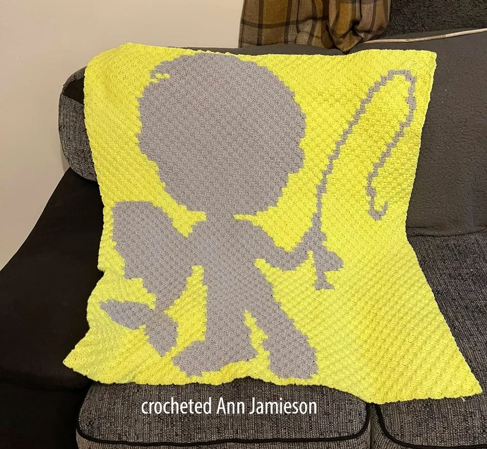 A crochet afghan featuring the silhouette of a child holding a fishing rod with a fish on the line.