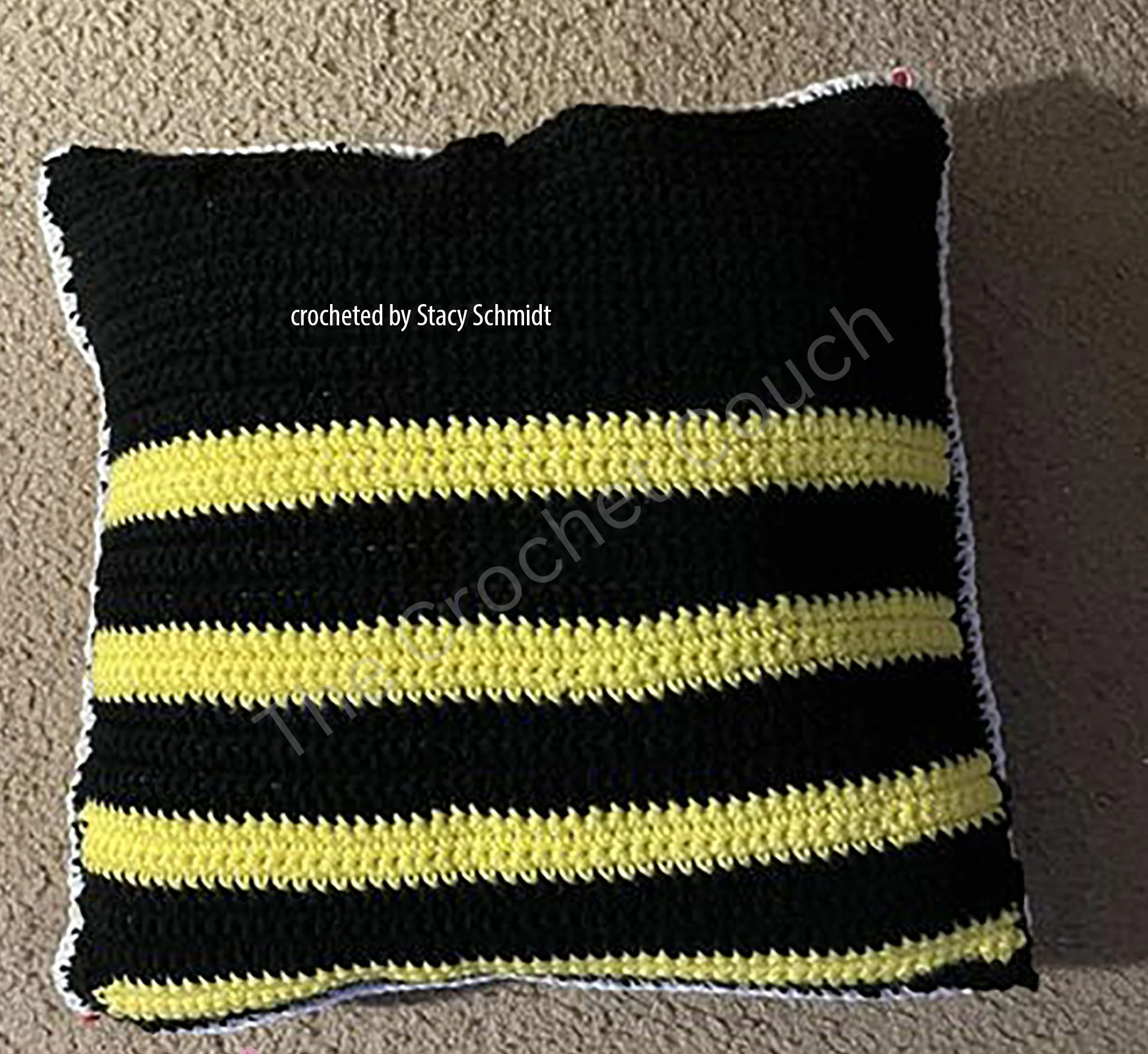 Crochet pillow with black and yellow stripes resembling bee colors, perfect for home decor or nature-themed projects.