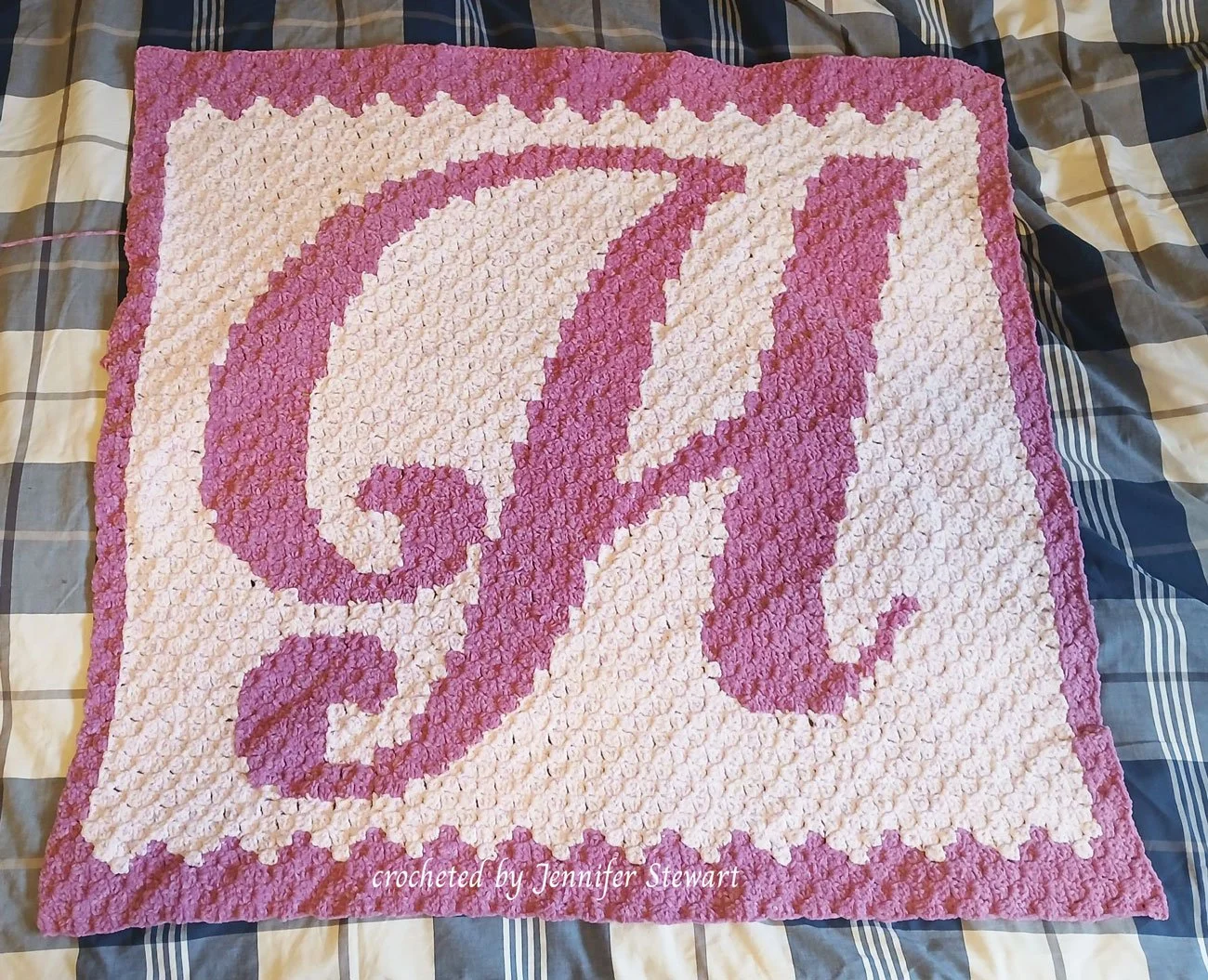 A corner to corner crochet afghan featuring a large, ornate letter H in a deep pink shade