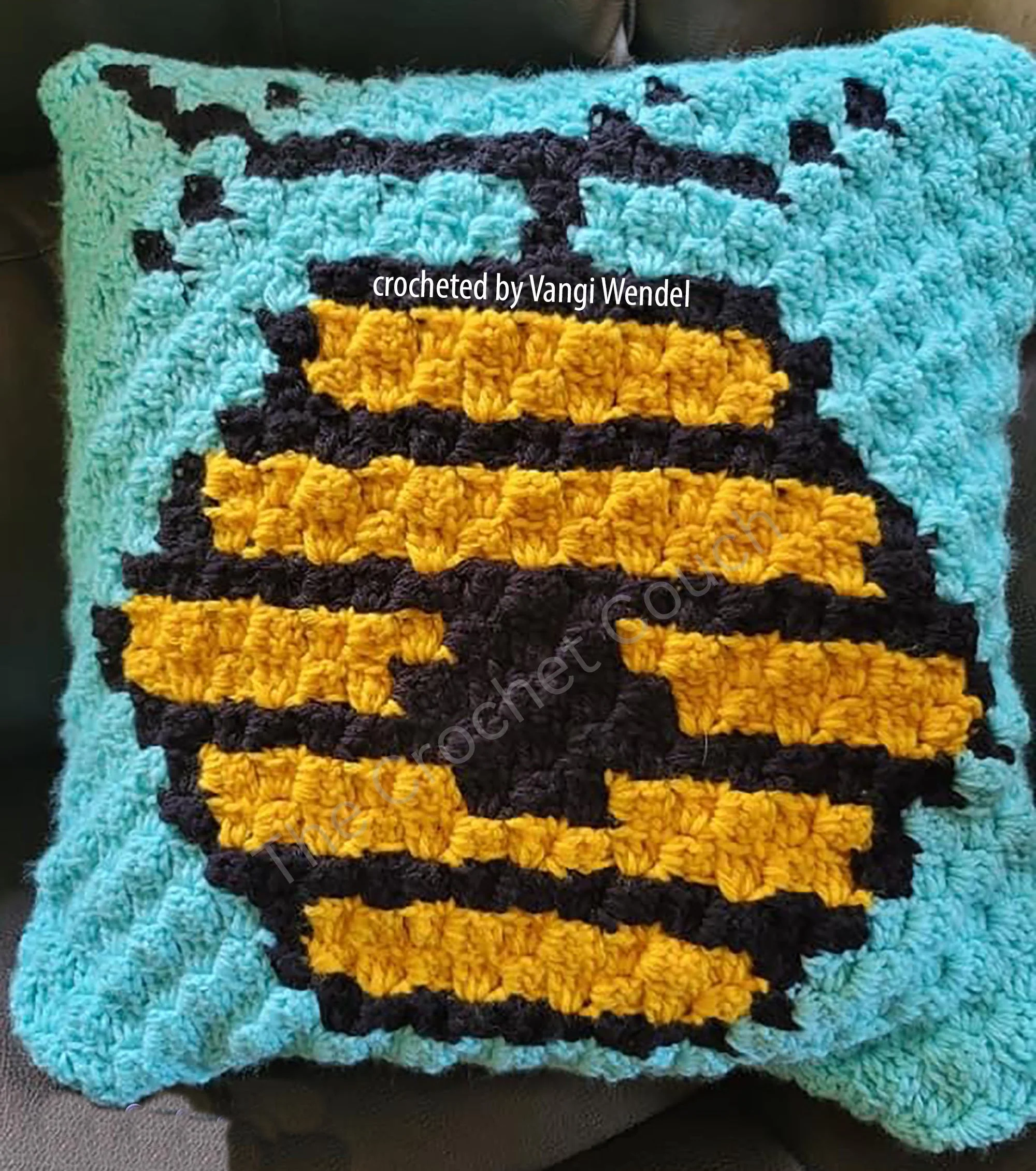 Crochet beehive pillow in bright yellow and black stripes with a blue background, made with the corner-to-corner technique.