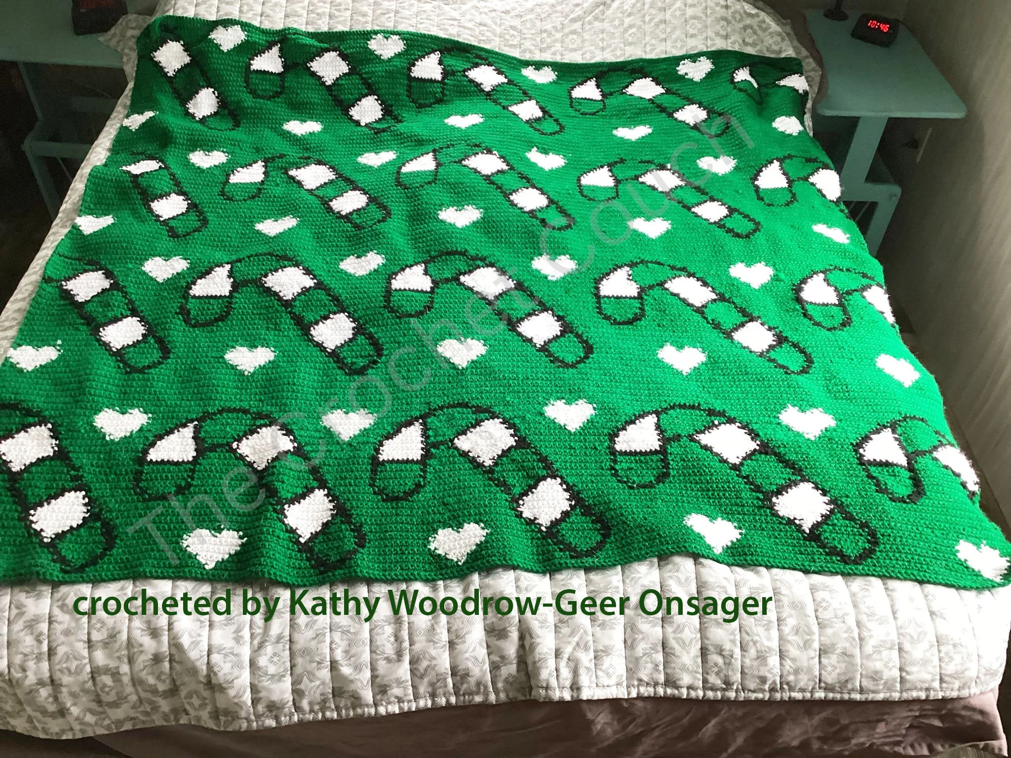 A bright green crochet afghan with a repeating design of white candy canes and hearts. The playful color combination offers a fresh take on festive holiday decor or handmade gifts.