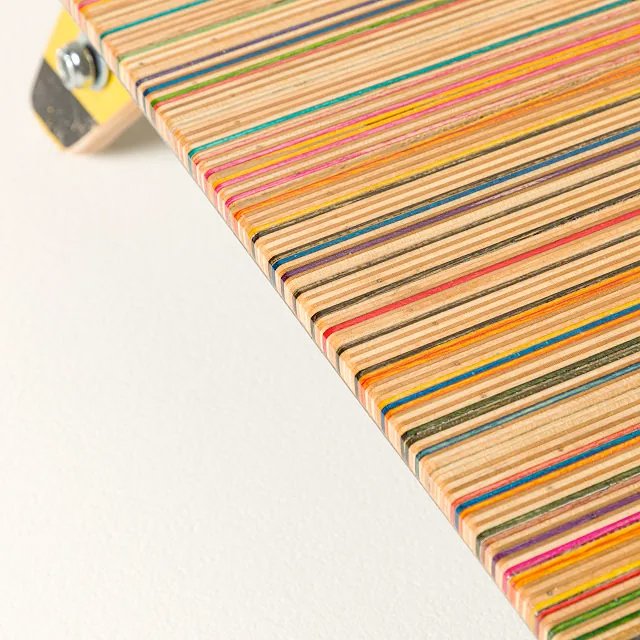 A Detail of the colorful top surface of the recycled skateboard display shelf. The colorful 7ply edge grain of the skateboards are used to create the top surface and are the focus of this image.