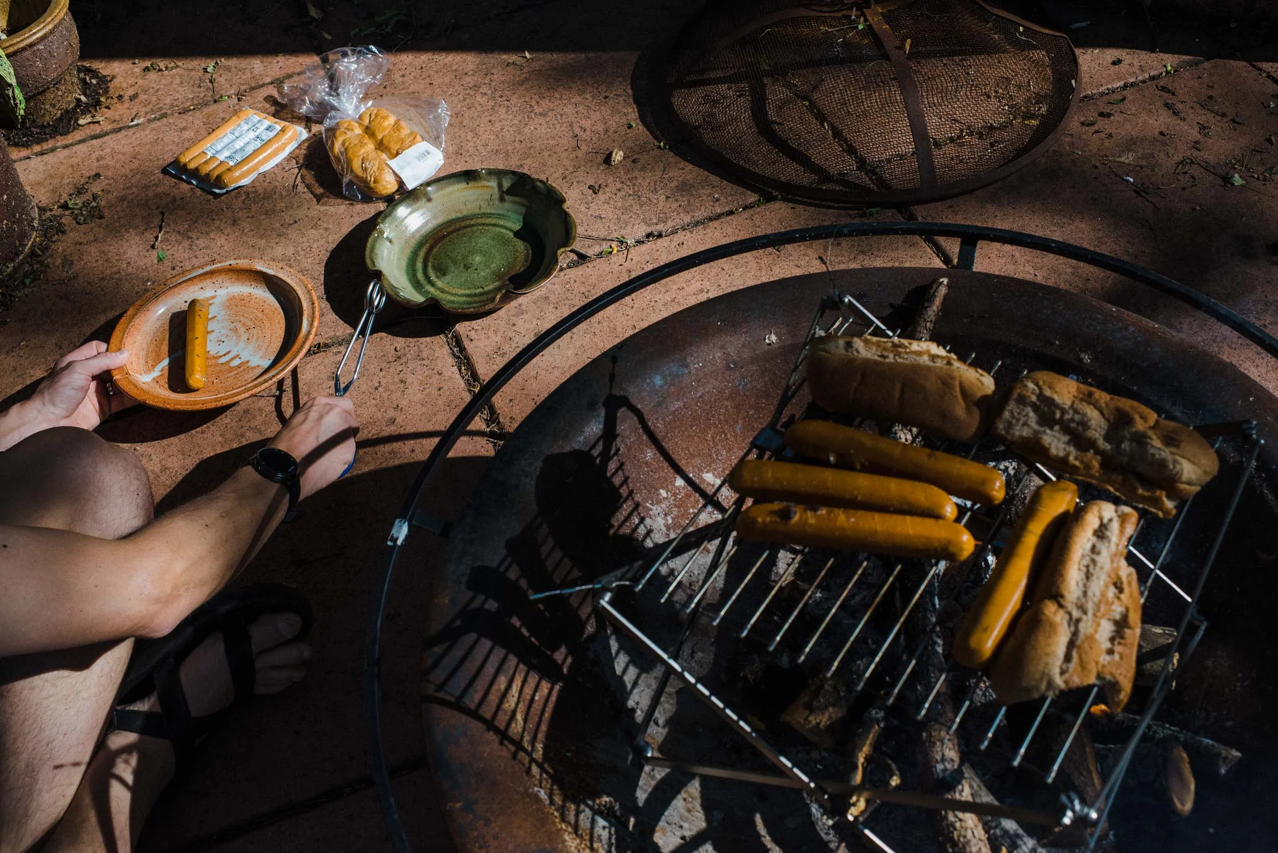 dad grilling hotdogs on the outdoor fire pit in the backyard