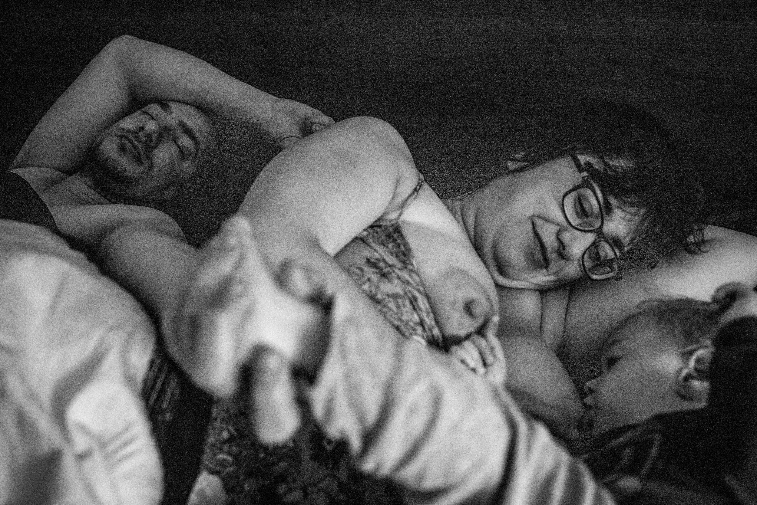 mom nursing her baby boy while dad sleeps.