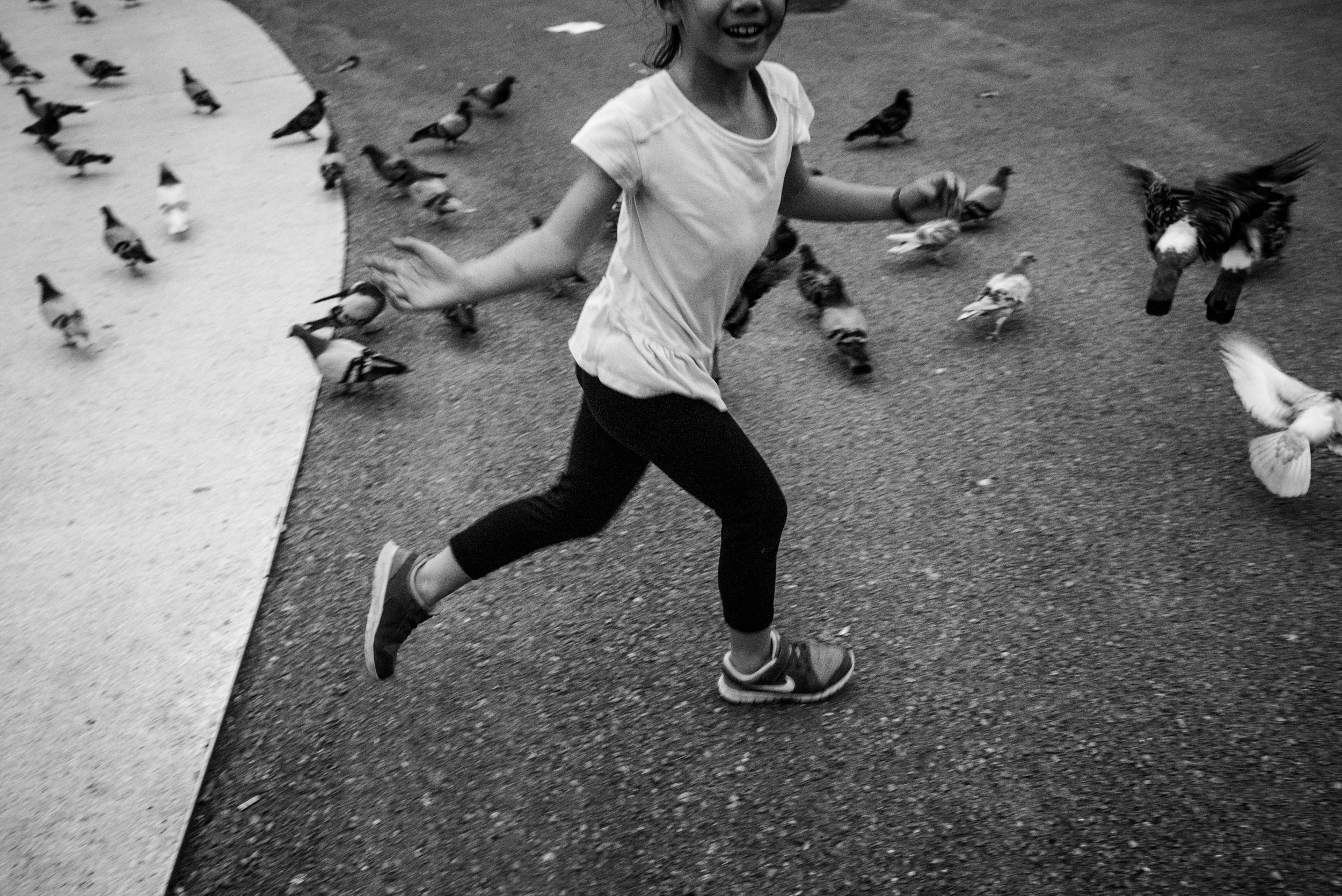 Vacation Day in the Life in Barcelona, Spain. Girl is chasing pigeons in Placa de Catalunya.