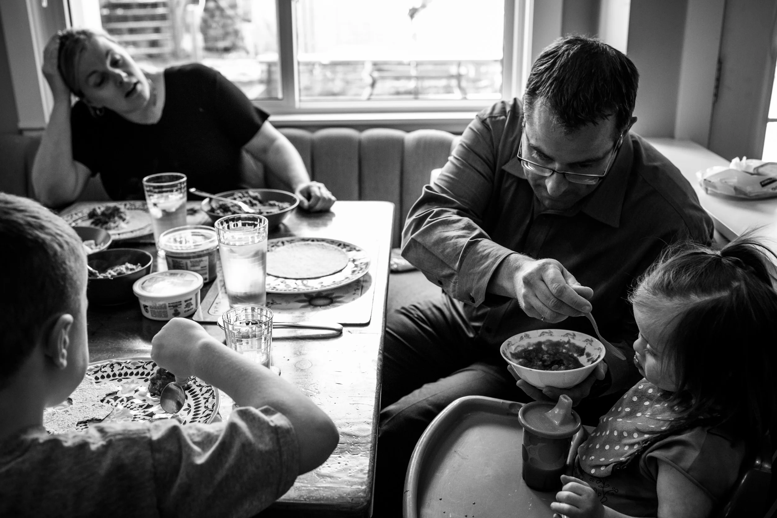Day in the life of Families. Exhausted parents feeding their children during dinner.