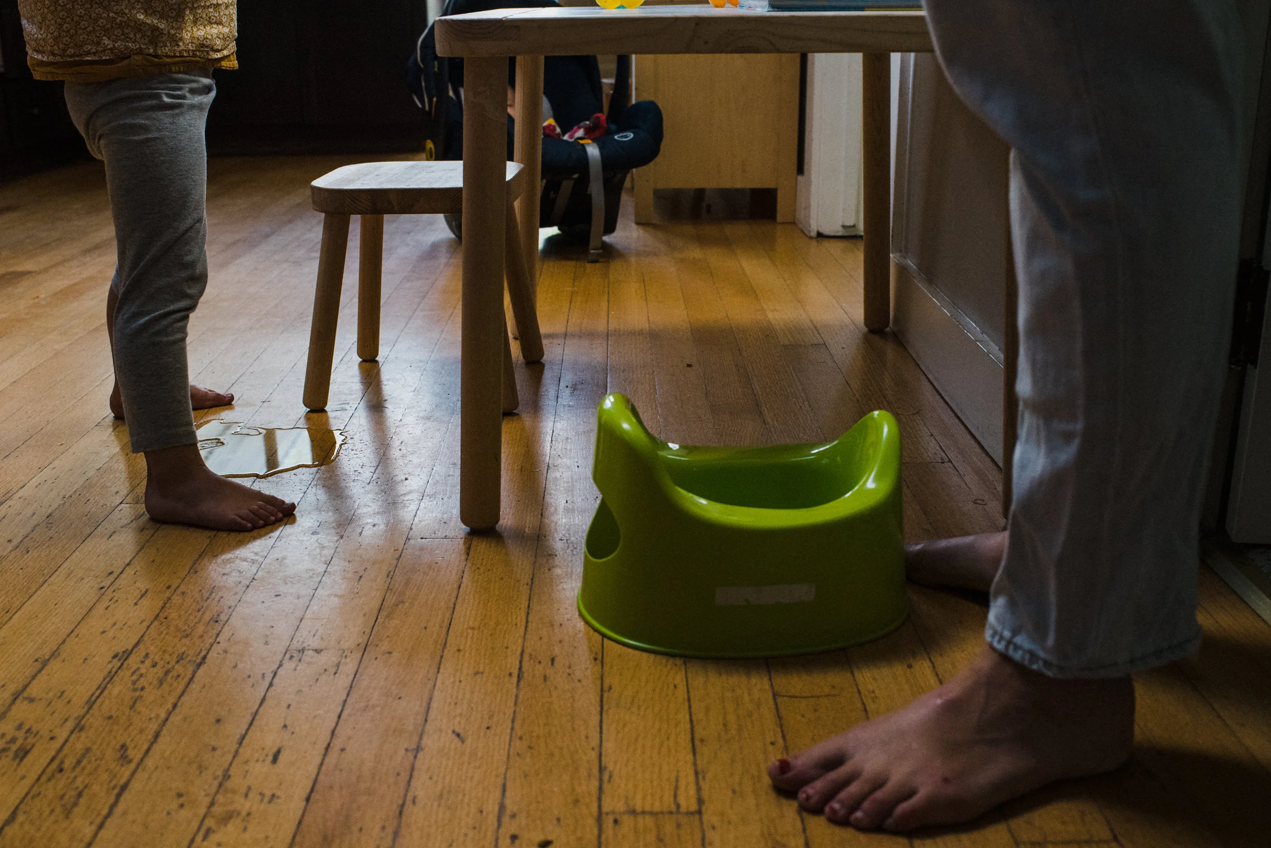 Day in the Life of Families. Girl peeing on the floor while standing in the kitchen.