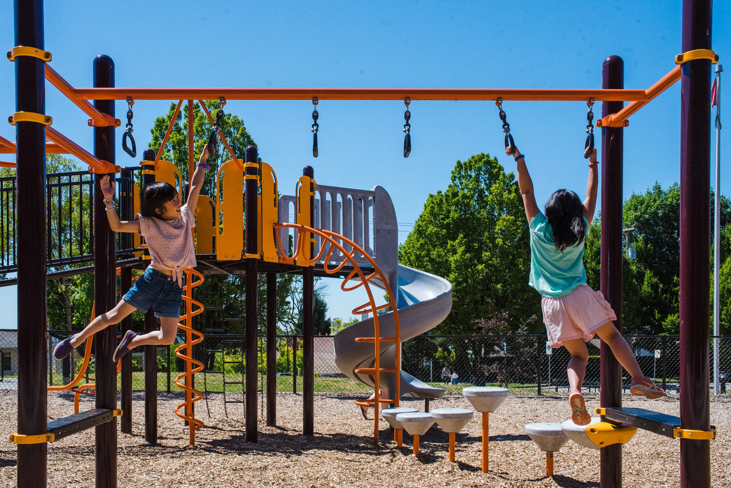 Playground photos. Sisters playing together on the monkey bar.