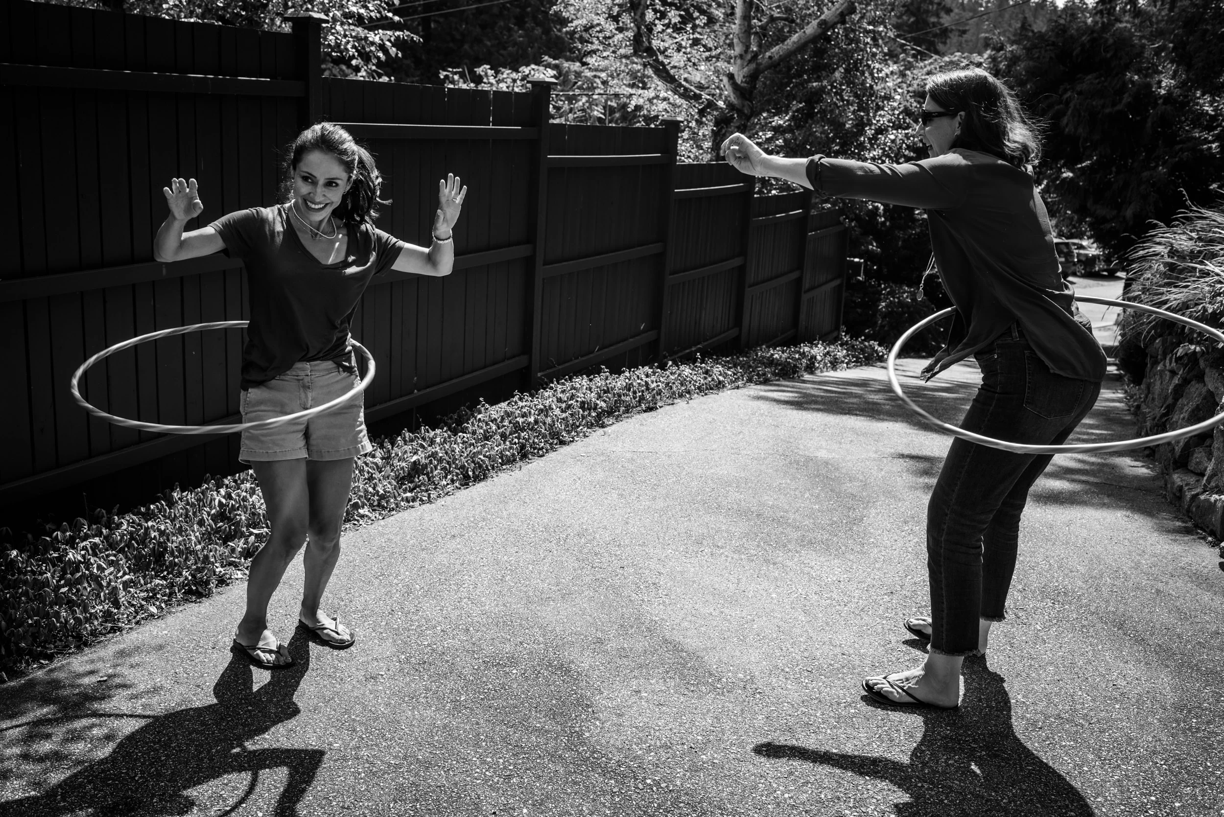 Day in the Life of a family. Sisters playing with hula hoops in the driveway.