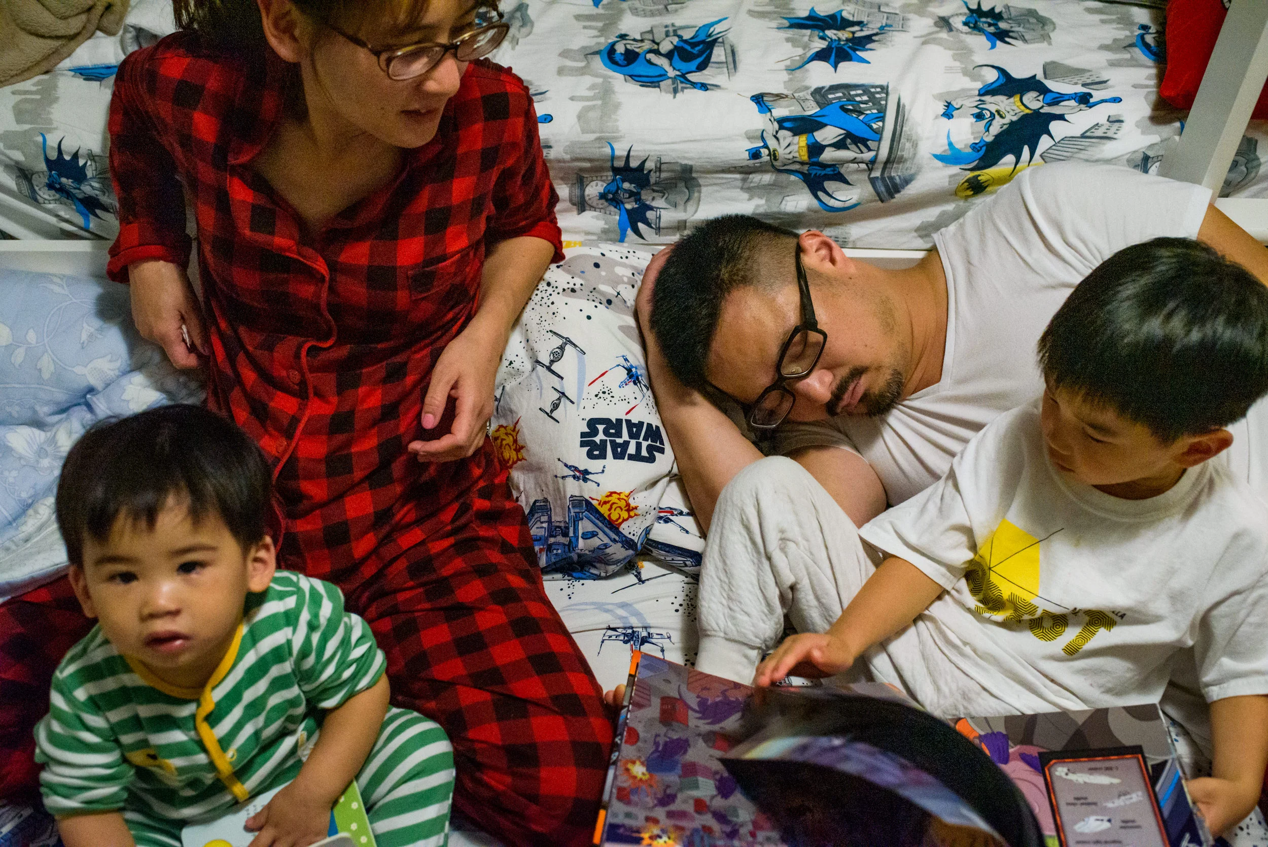Day in the Life of Families. Dad falls asleep during bedtime reading with his boys.