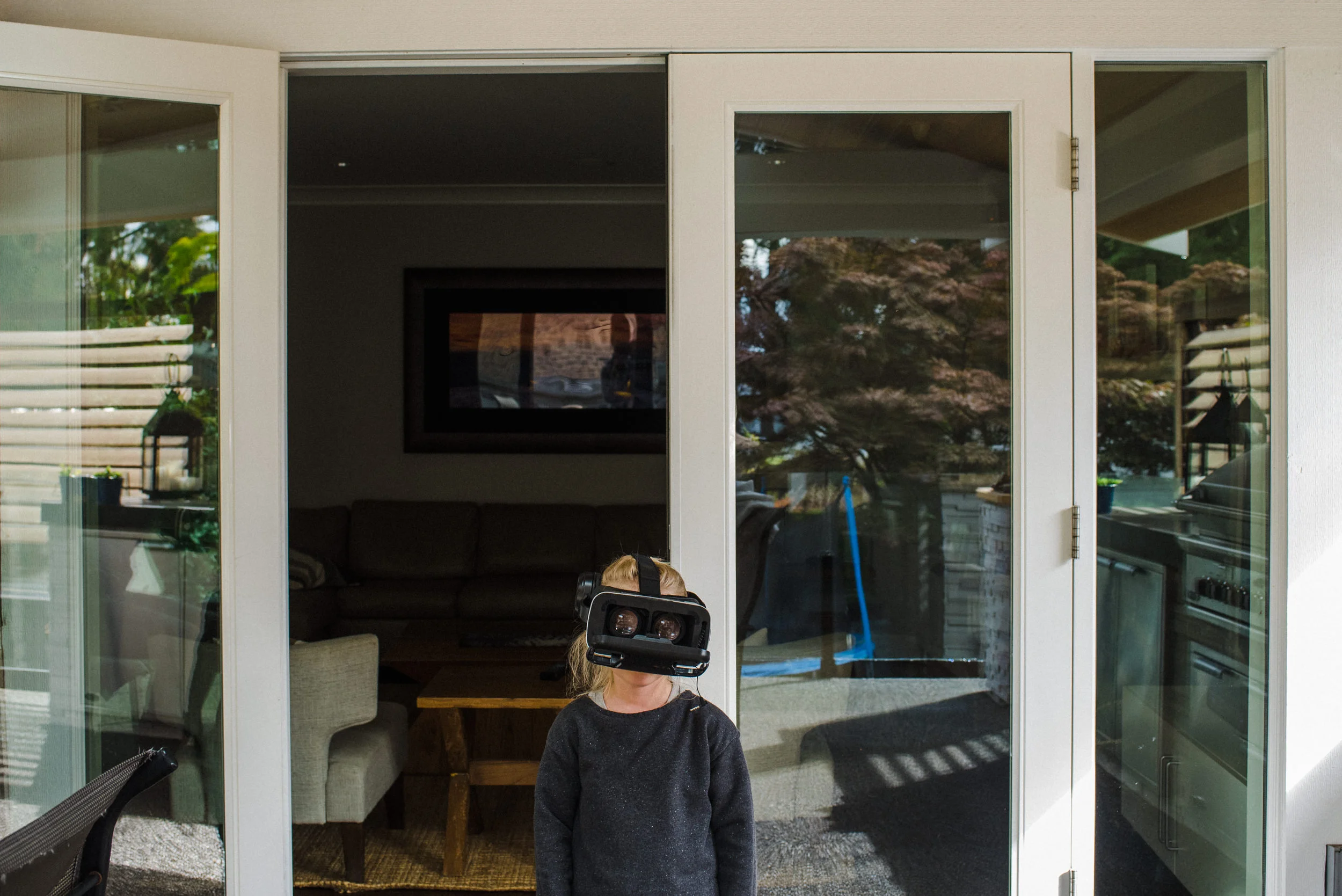 Environmental portrait of a girl. Girl wearing a virtual reality eyewear looking out into the backyard.