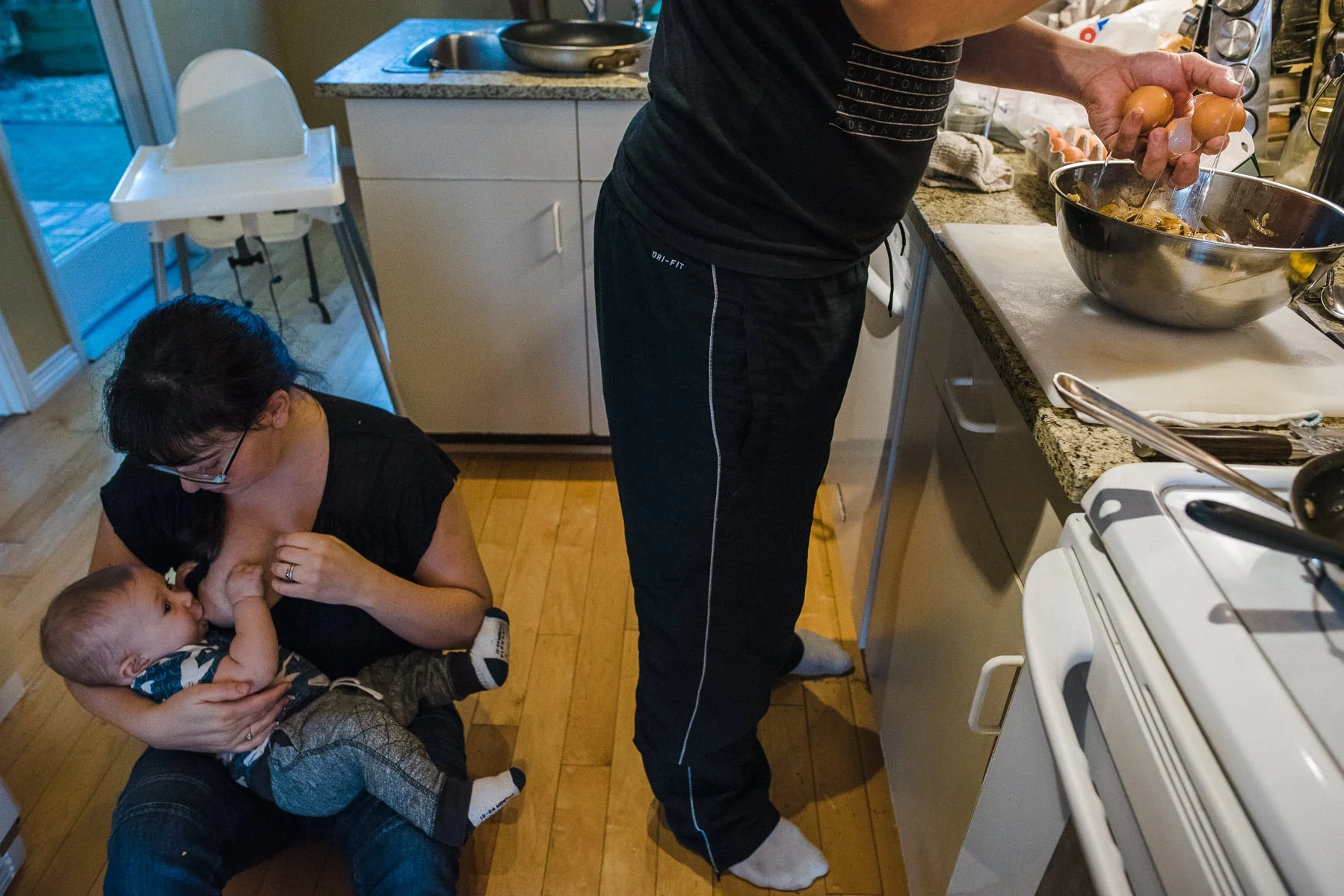 Family Day in the life. Anytime is a good time for breastfeeding. Like mom breastfeeding in the middle of the kitchen floor while her husband makes breakfast beside her.