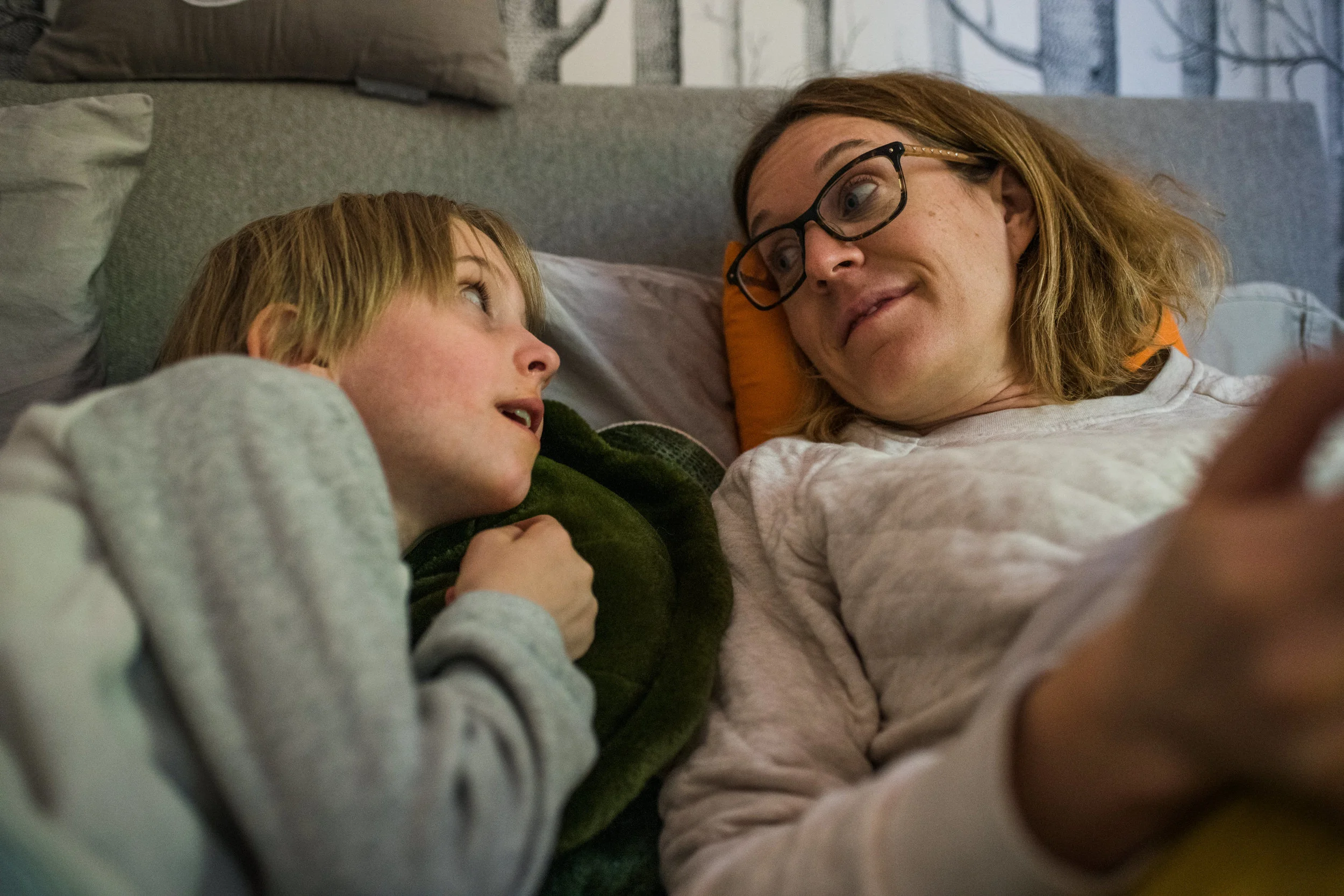 Mom and daughter bonding over bedtime stories while lying in bed.