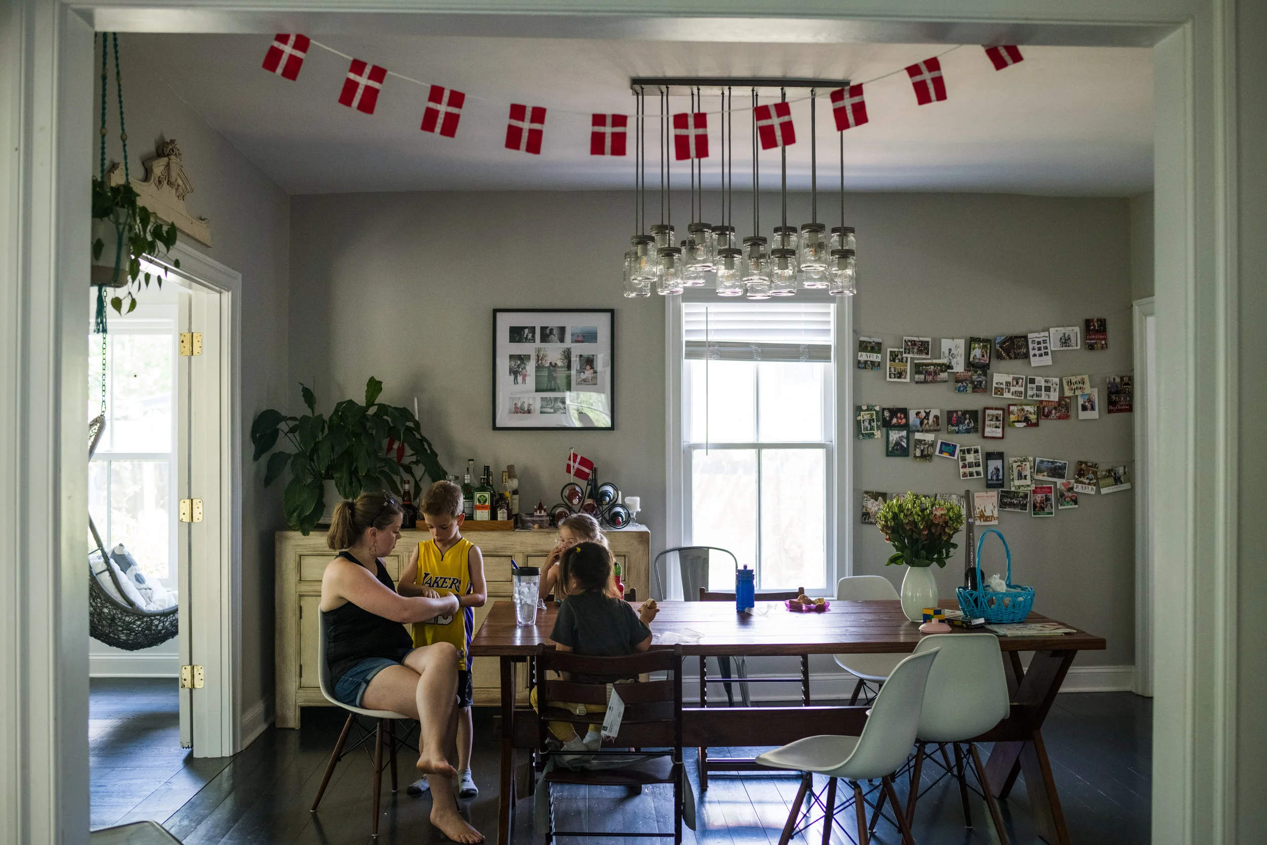 Mom helping her son with a cut while her other children watch from the kitchen dining table.