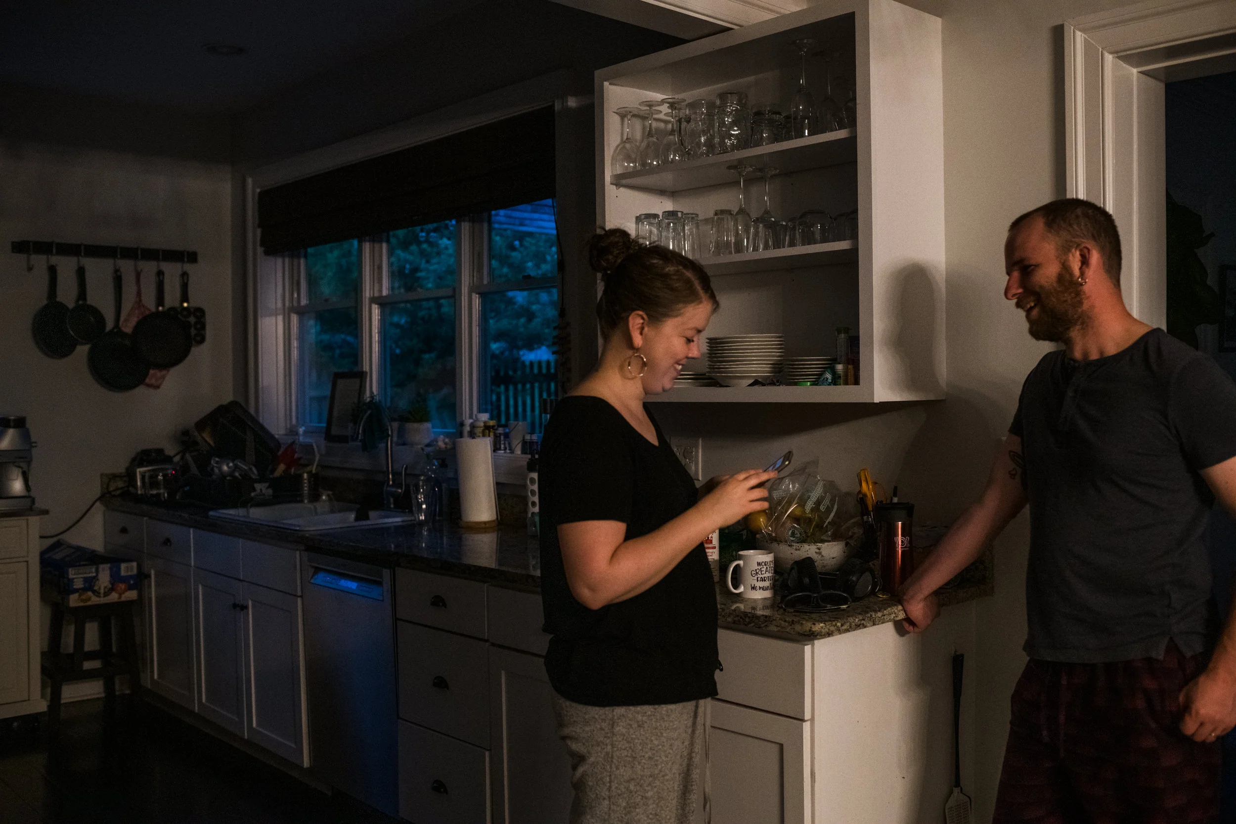 Parents sharing a laugh in the kitchen at the end of a family day.