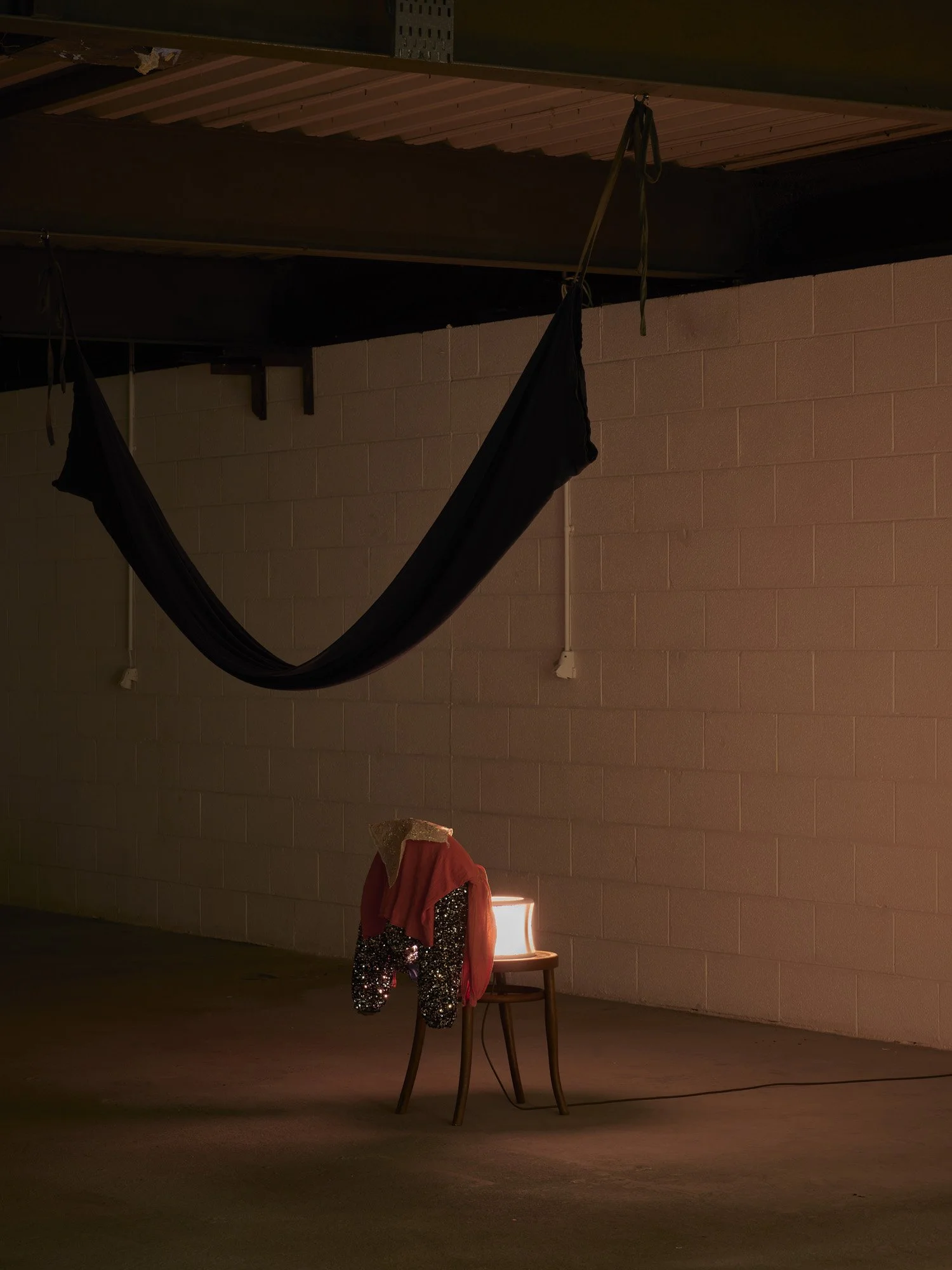   Aleana Egan ,  home and the world , 2026. Chair, light, dyed jersey cotton, MDF, clothes, shell, glue, marine ballast, dimensions variable. Installation view, Interface, Inagh. Courtesy of the artist and Kerlin Gallery. Photograph by Ros Kavanagh. 