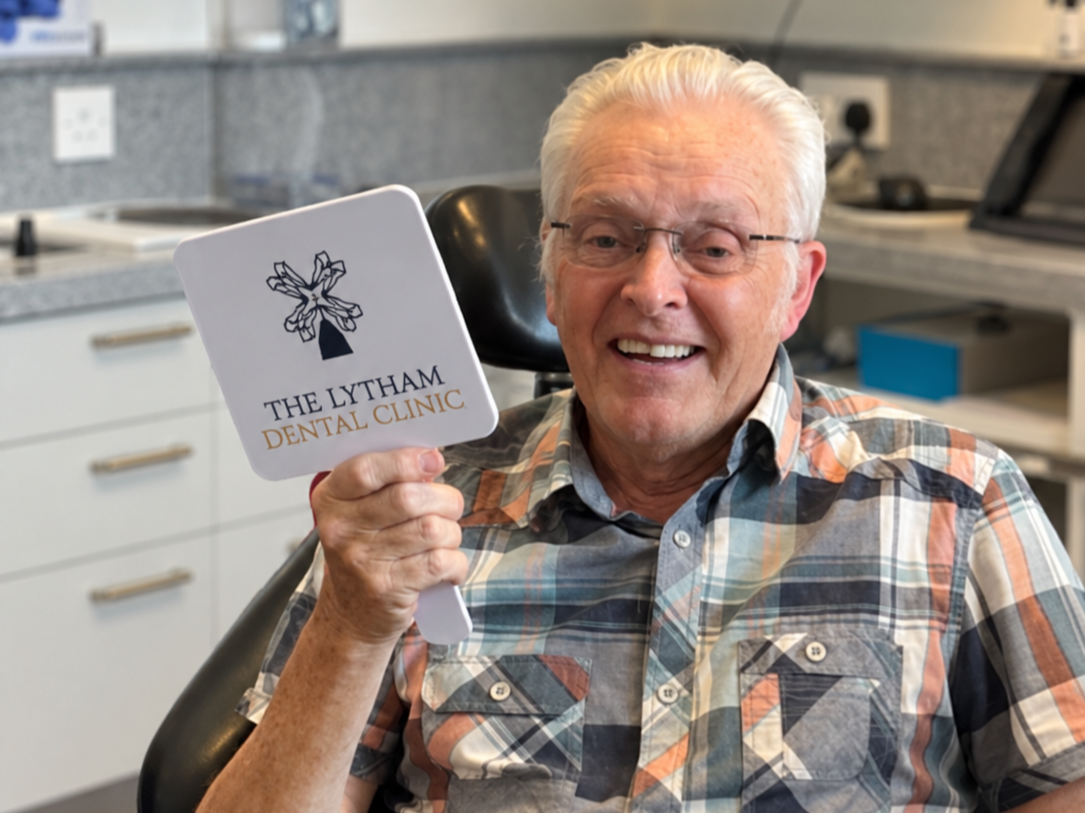 Smiling patient at The Lytham Dental Clinic in Lytham St Annes, holding a mirror during his dental appointment.