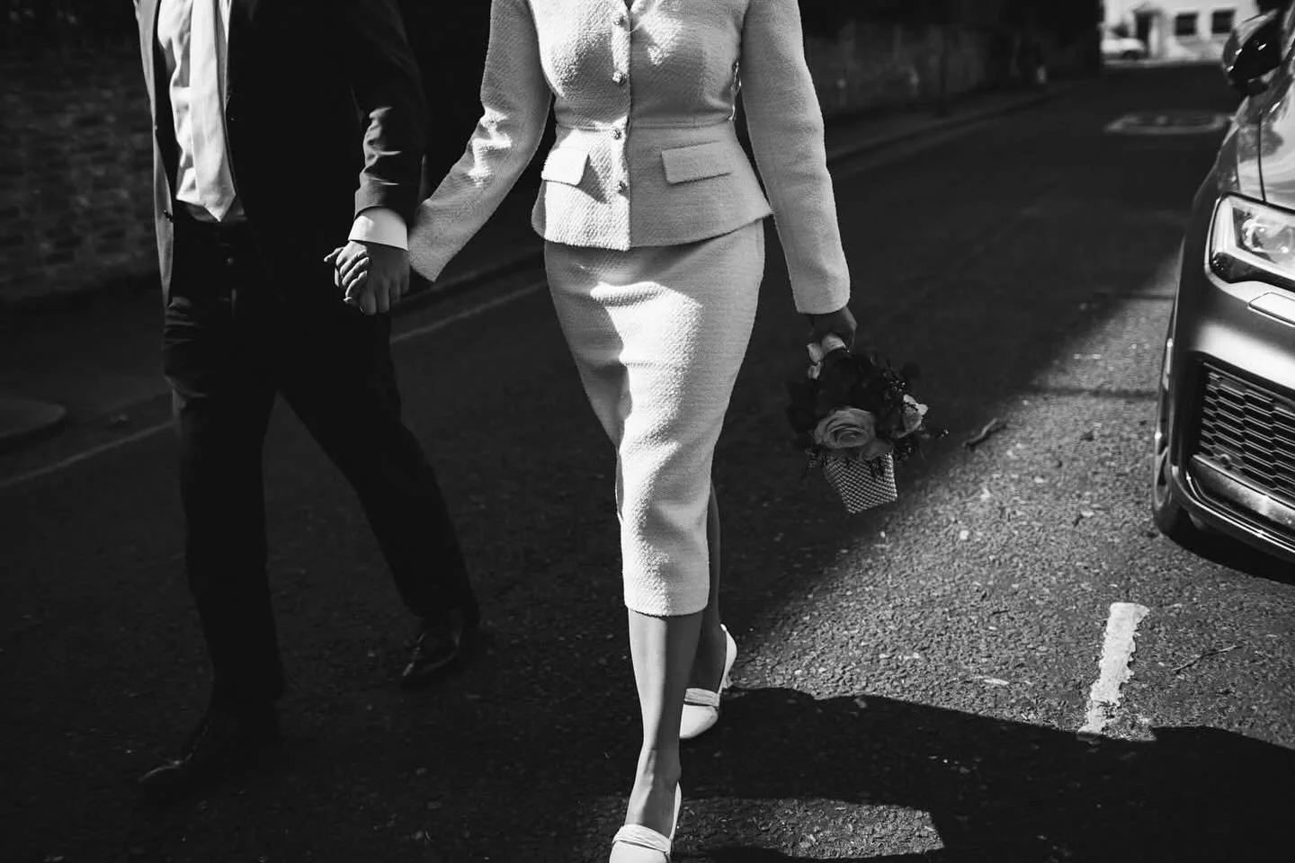 In this black and white photograph from Georgia and Toby&rsquo;s wedding at Chelsea Town Hall, elegance meets authenticity in the most effortless way. The newly married couple walk hand in hand through the quiet backstreets of Chelsea, one of London&