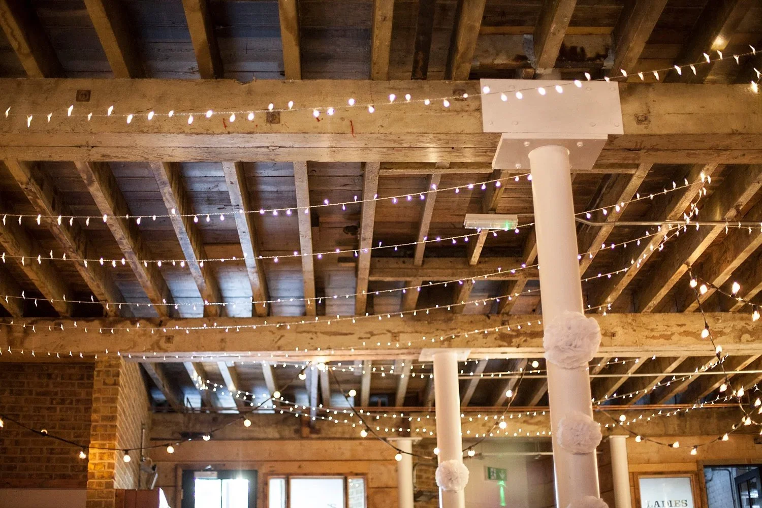 Industrial wedding interior with exposed beams and warm lights at 100 Barrington in Brixton