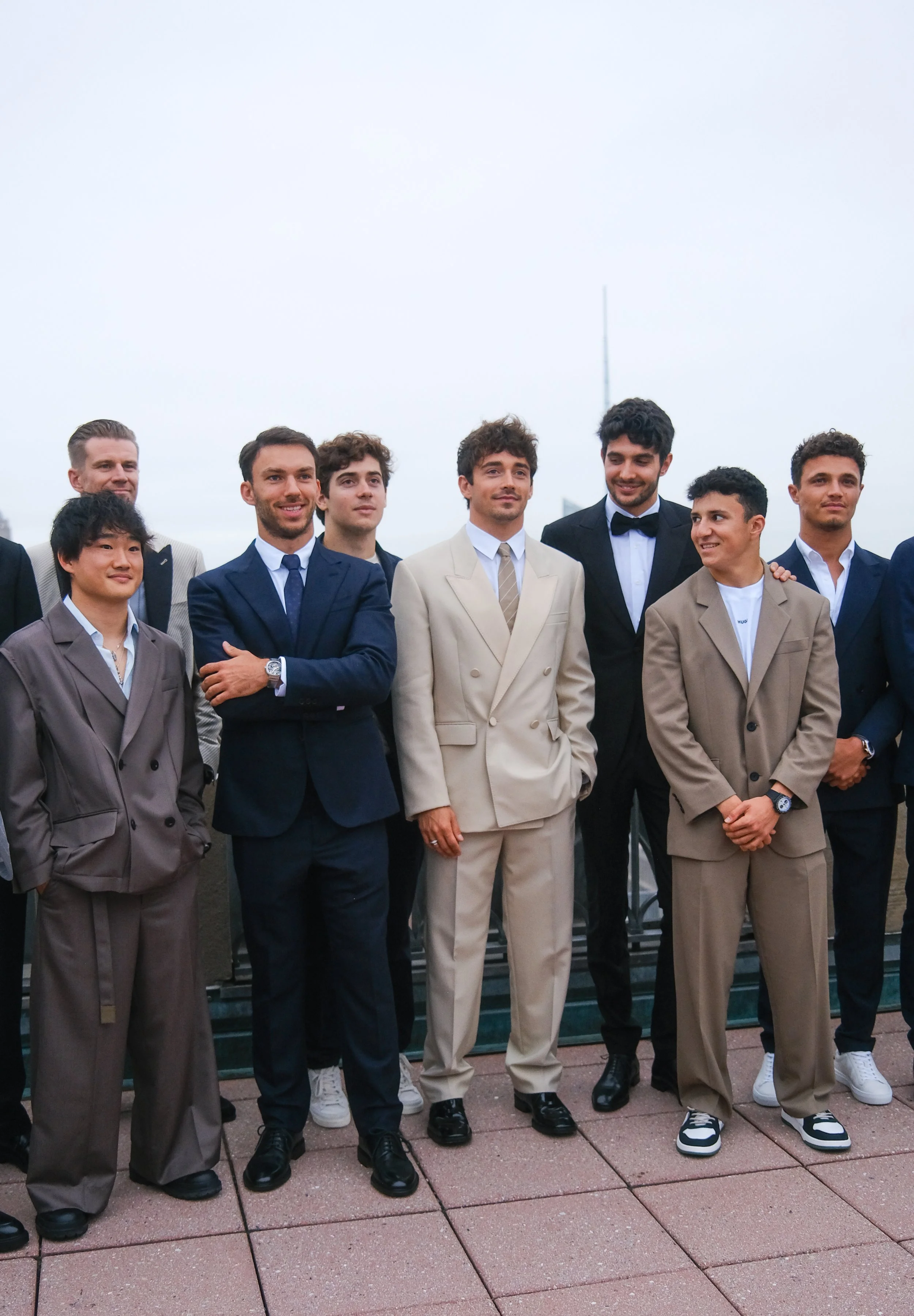 Group of men dressed in formal suits standing outdoors on a cloudy day.