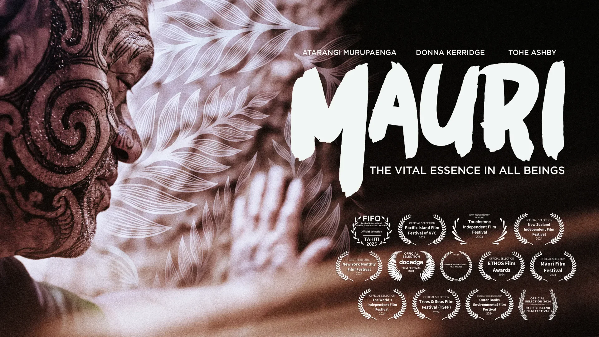A film poster for the moving 'Mauri - the vital essence of all beings' featuring a man with a fully tattooed face smiling while touching what looks like a textured leaf. Click for details.