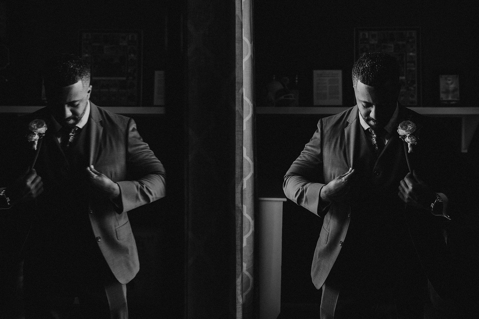 Black and white photo of a man in a suit, holding roses, looking down, with a mirror reflecting his posture.
