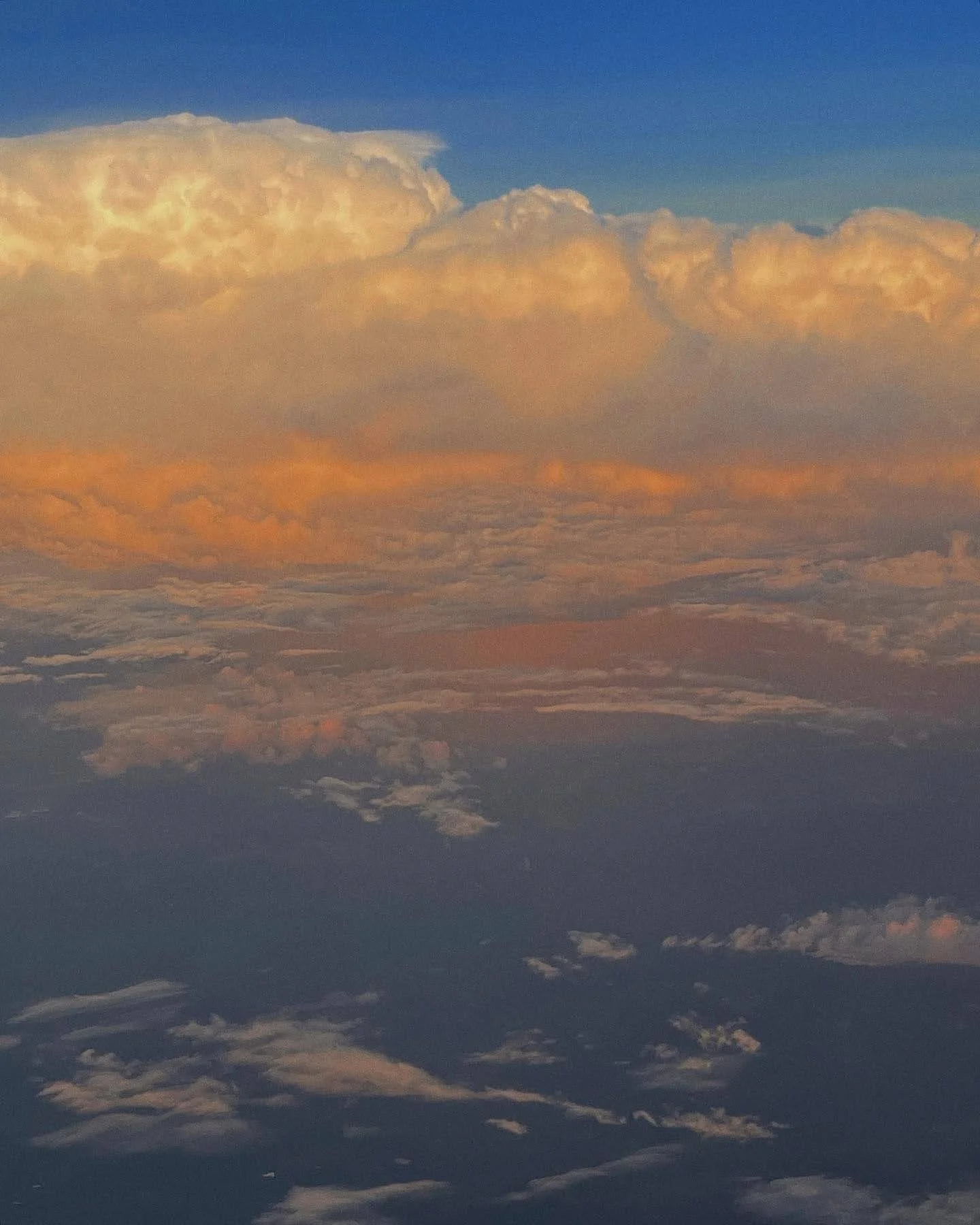 Aerial view of clouds at sunset or sunrise, with golden and blue hues in the sky.