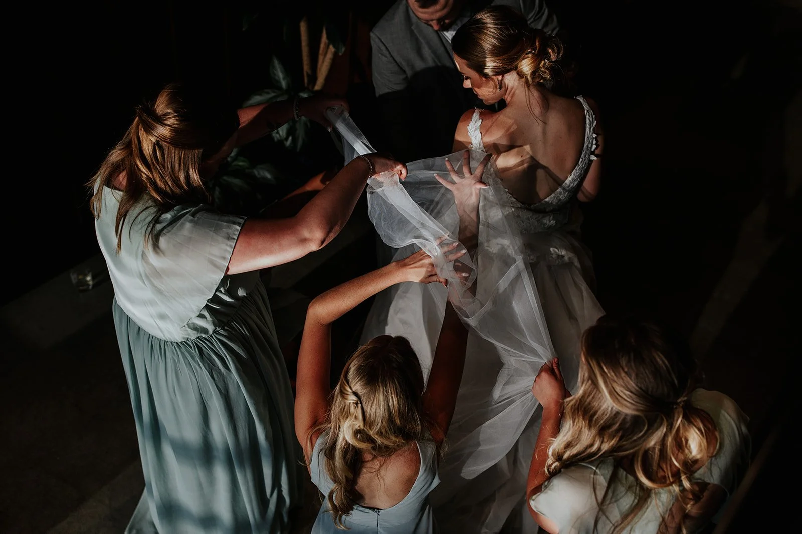 People helping a bride with her wedding dress.