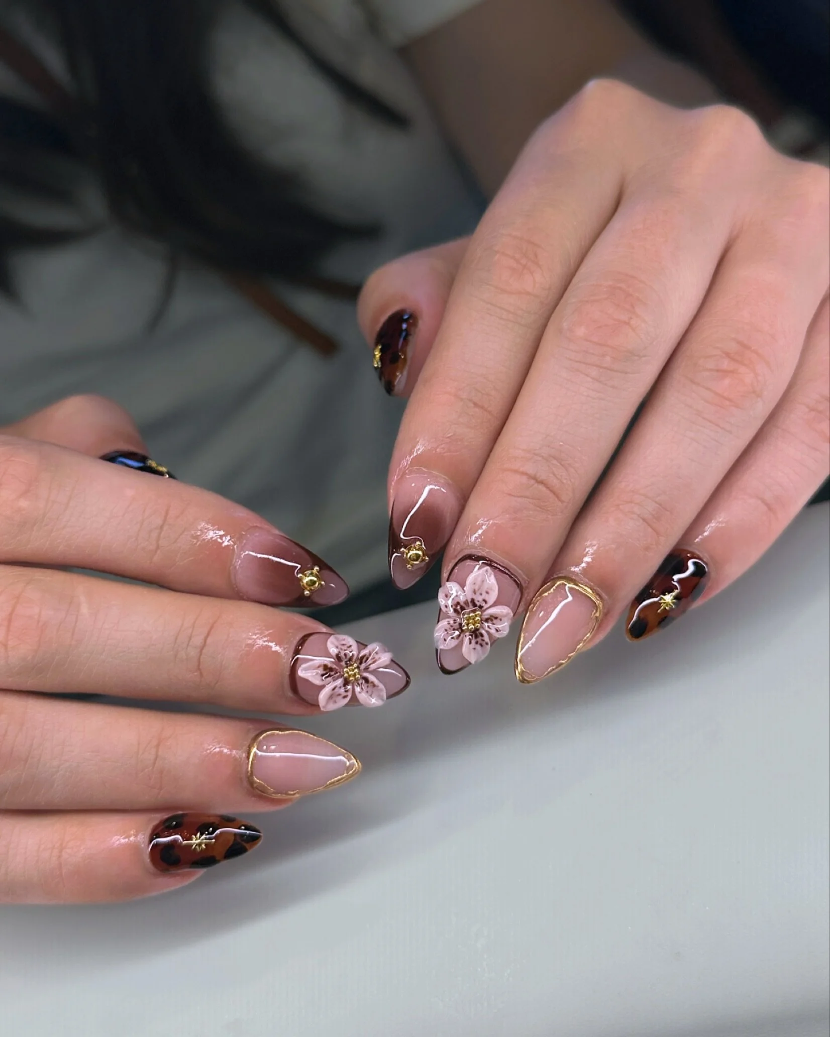 🍂✨ Fall in Bloom ✨🍂
Ashley&rsquo;s latest creation blends tortoiseshell tones, gold accents, and 3D florals for a look that&rsquo;s equal parts bold and romantic. The soft blush base meets rich caramel and chocolate hues &mdash; finished with hand-