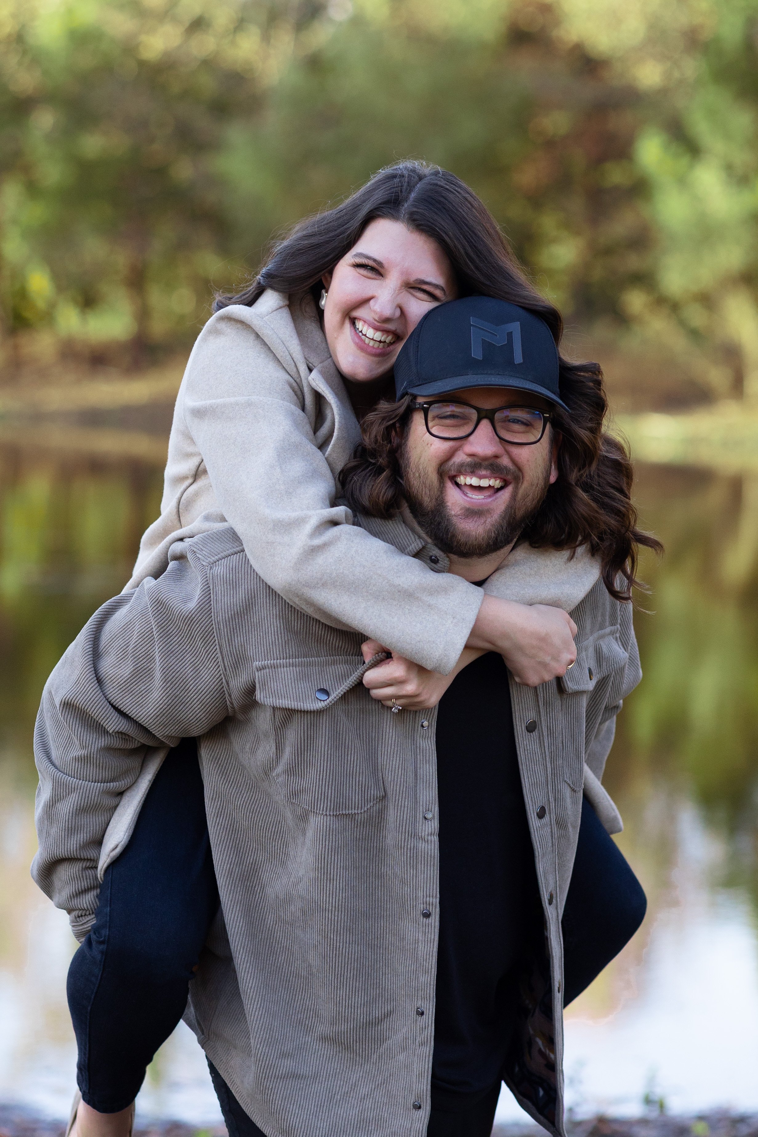 a Man and a woman by a lake smiling and doing videography