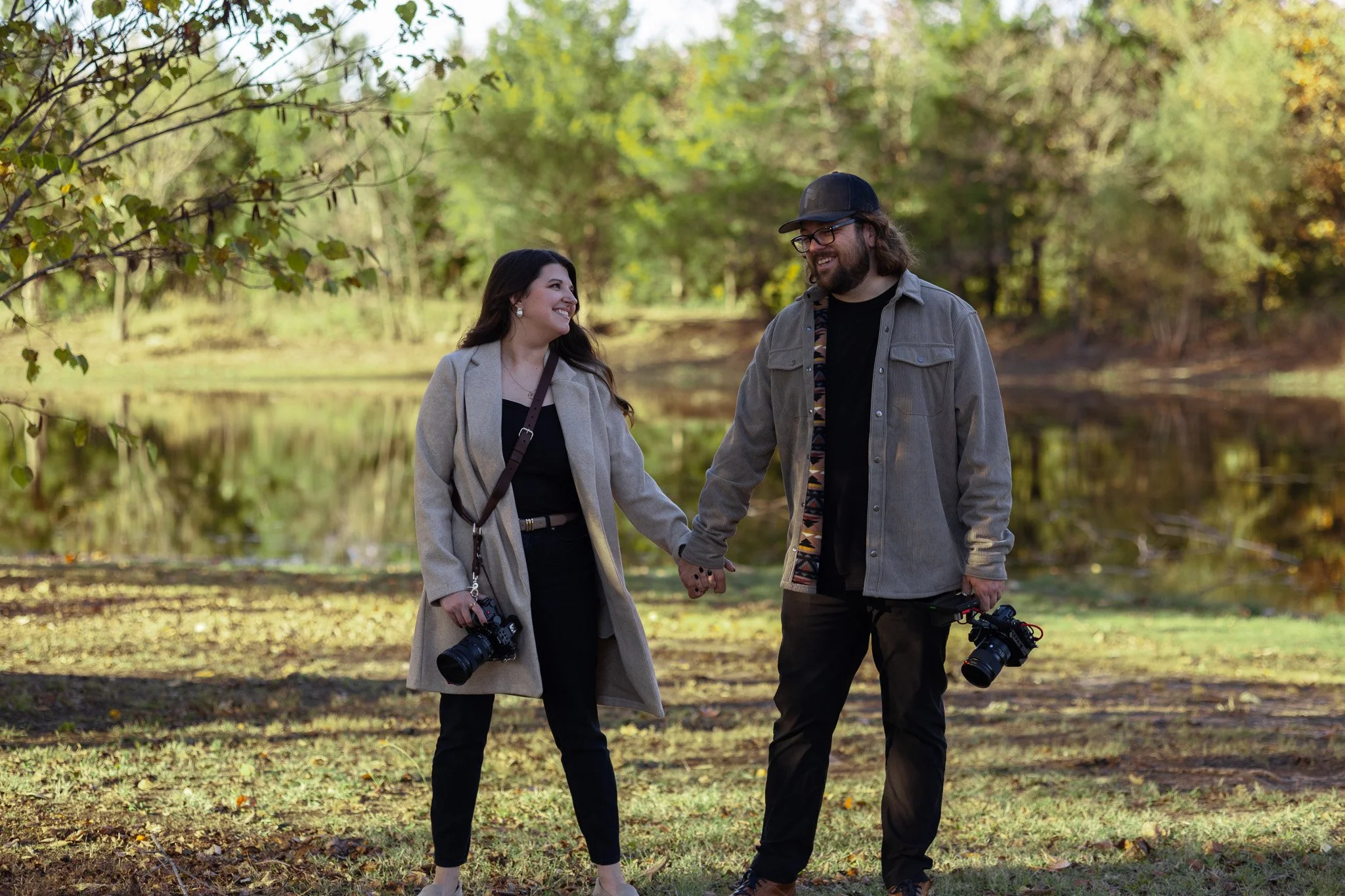 Man and woman laughing by a pond in summer