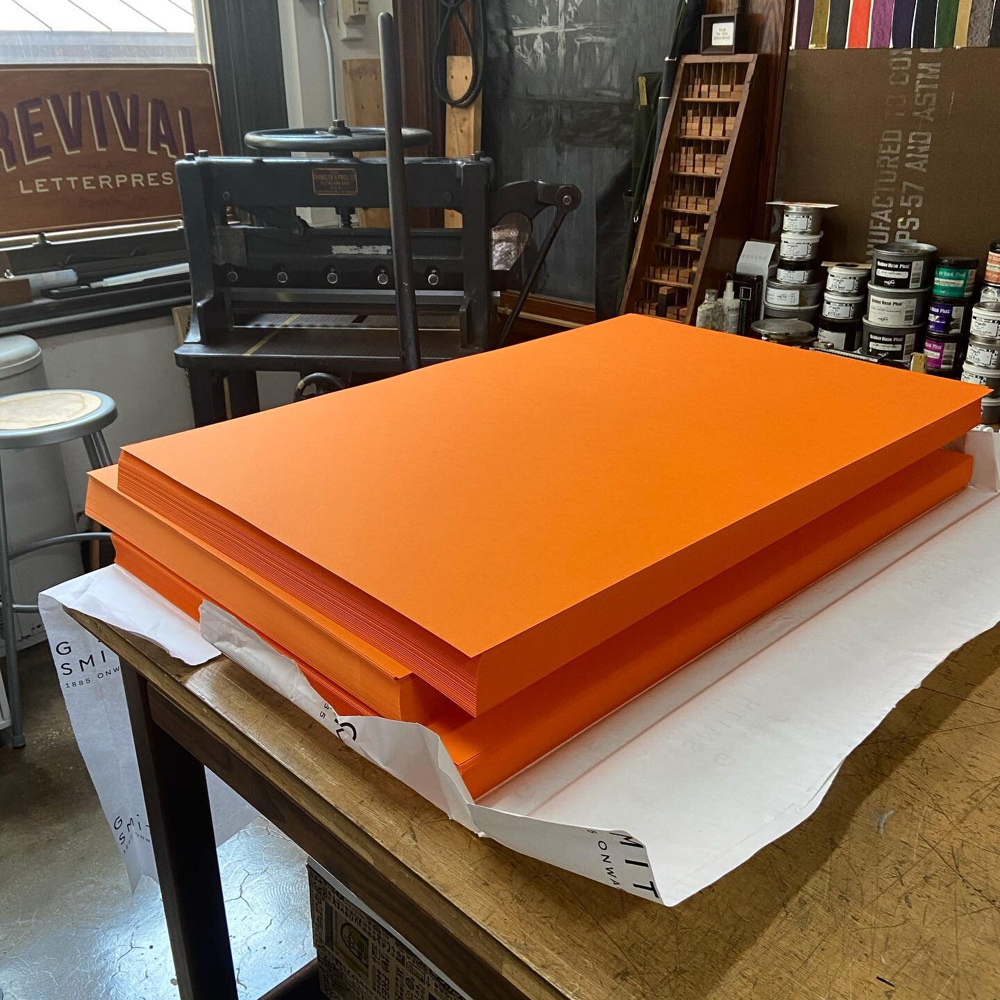 3 cases of Colorplan Mandarin 350gsm cover stock ready to be trimmed on a 1918 Chandler &amp; Price manual guillotine