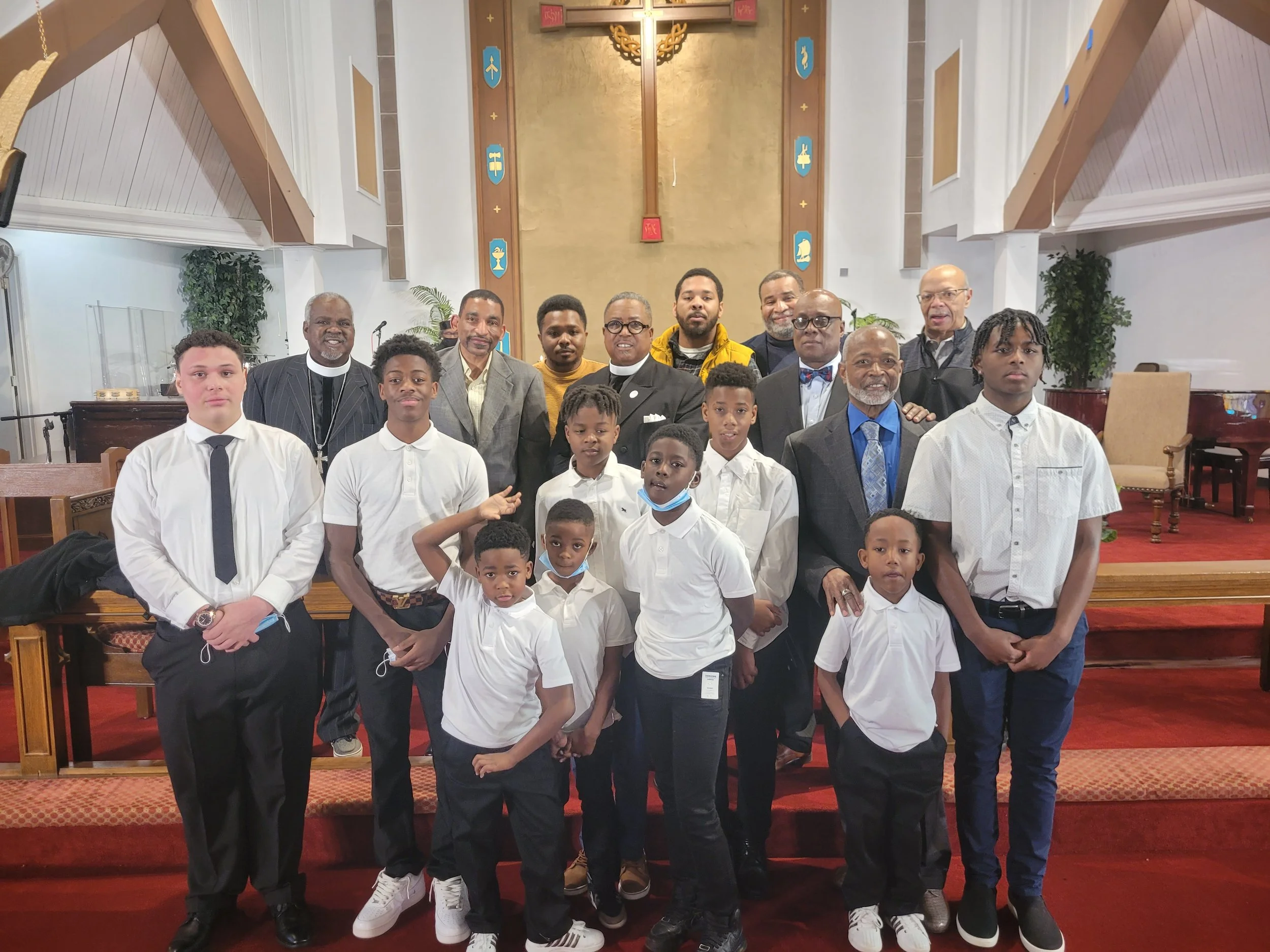 A group of people, including children and adults, is gathered together in a church, dressed in formal and casual attire, for a photo on the church's altar.