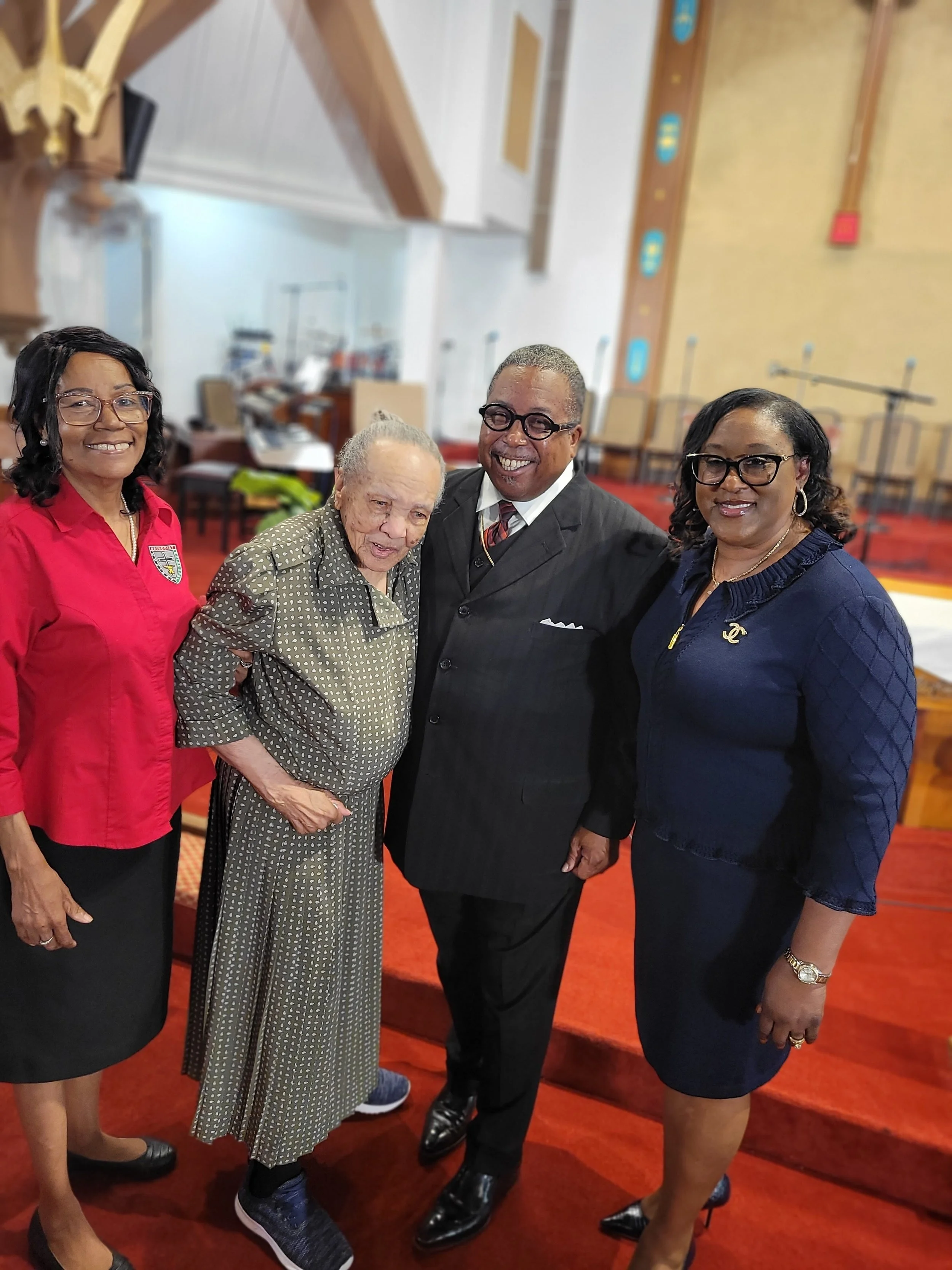 Four people standing together in a church, smiling for the camera.
