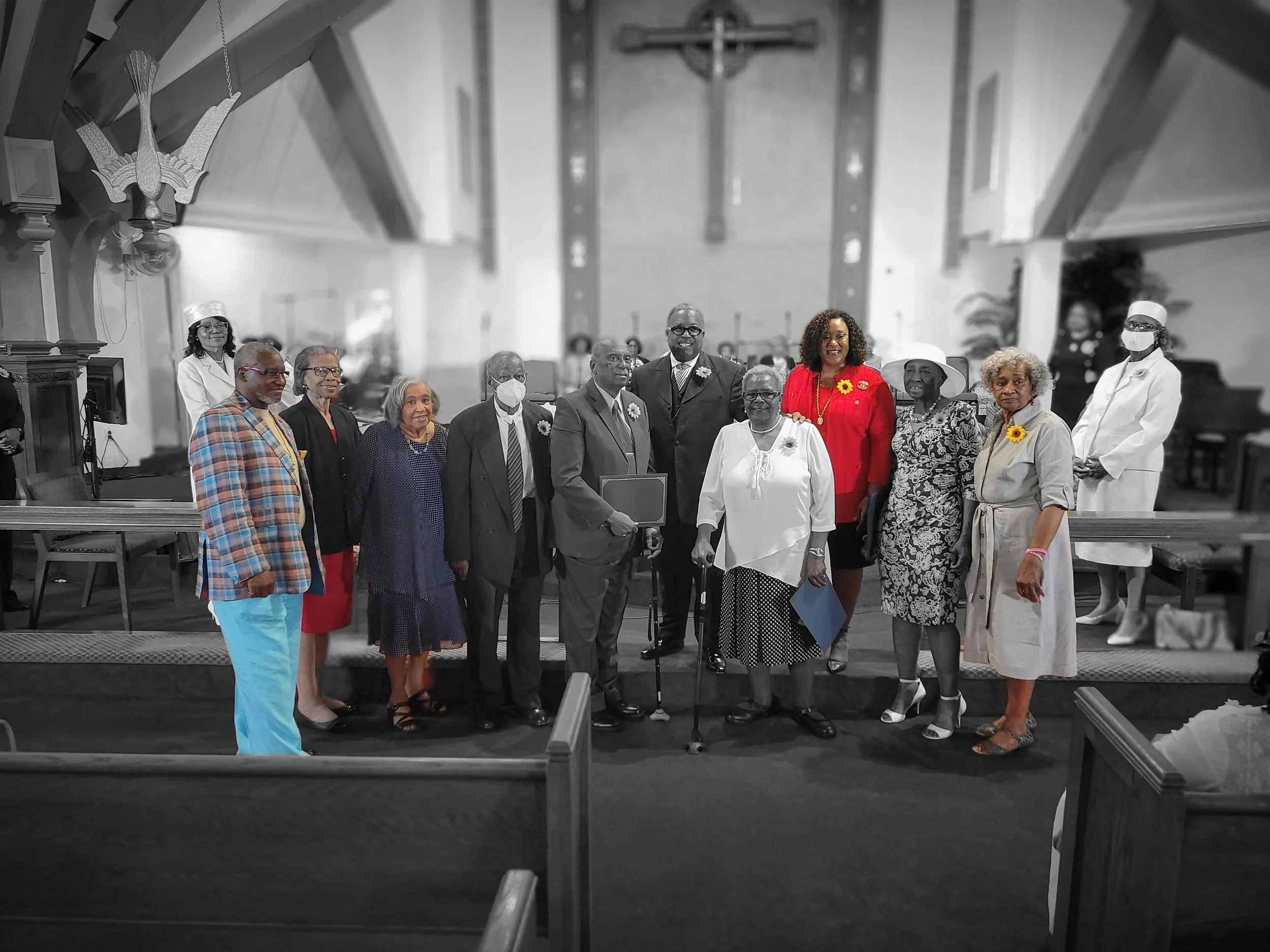A group of people standing inside a church, with some in color and others in black and white. The background features the church altar.