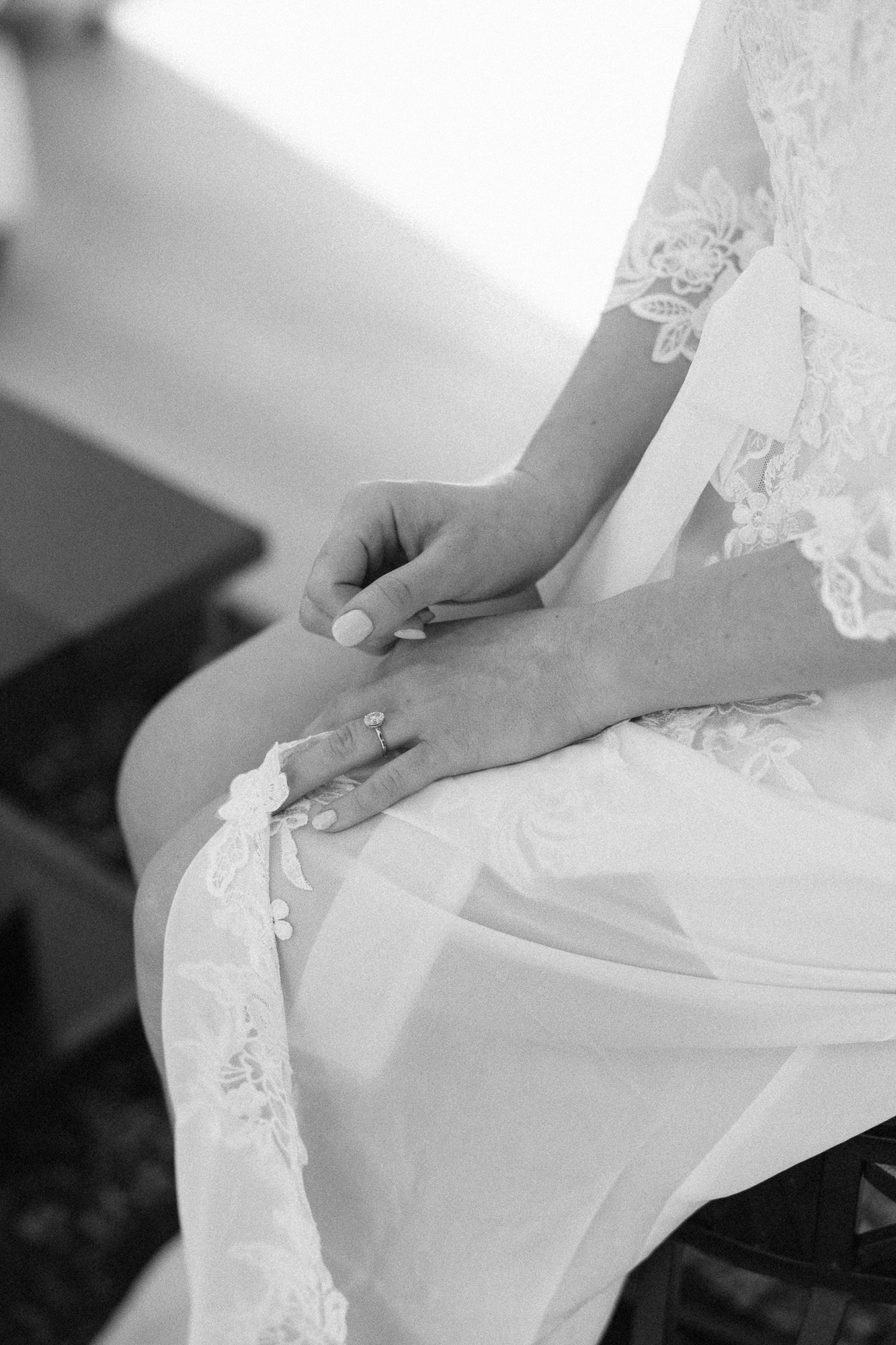 womans hands folded on lap on lacy white robe