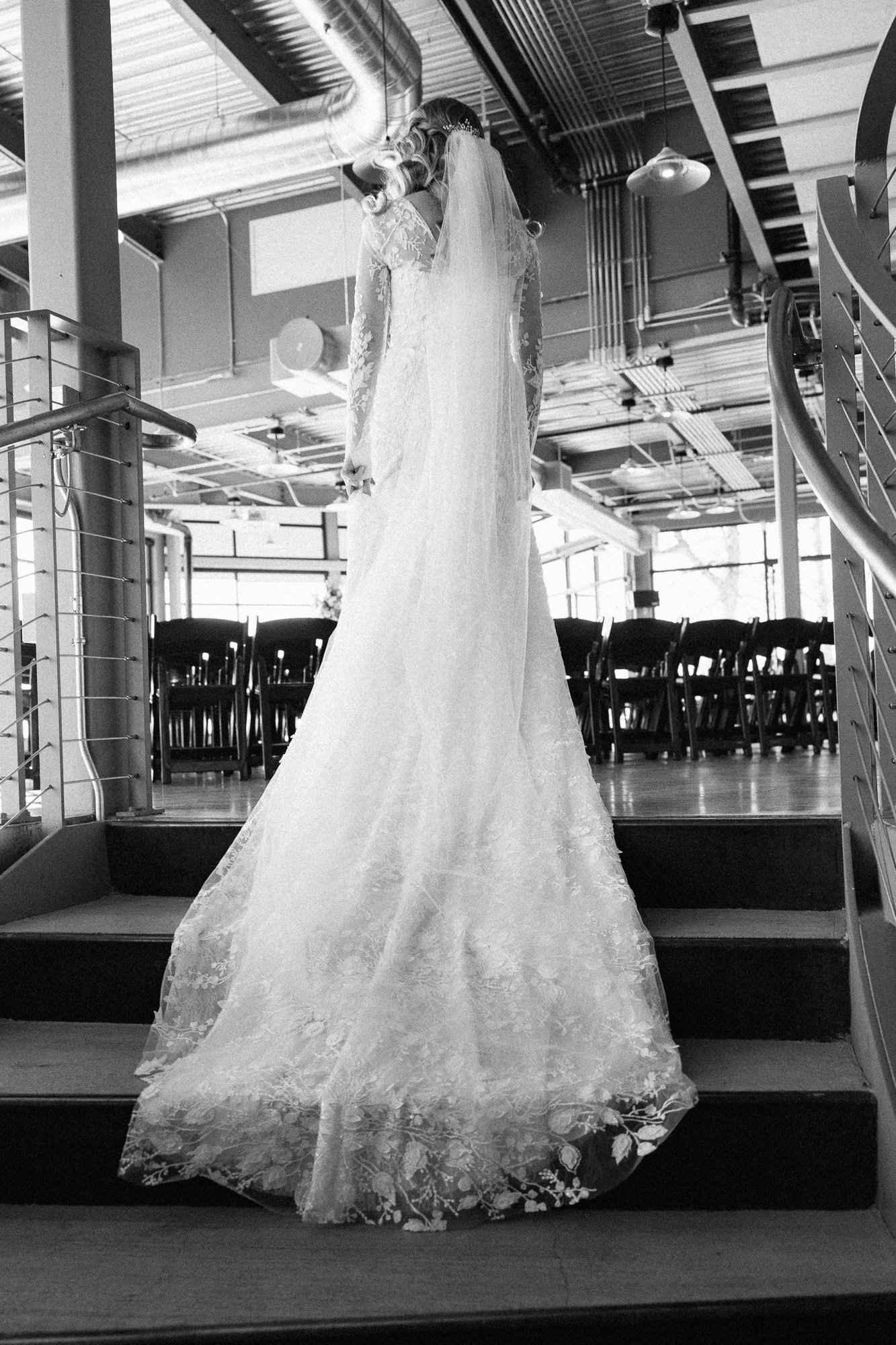 train of white wedding gown drapes down a set of stairs