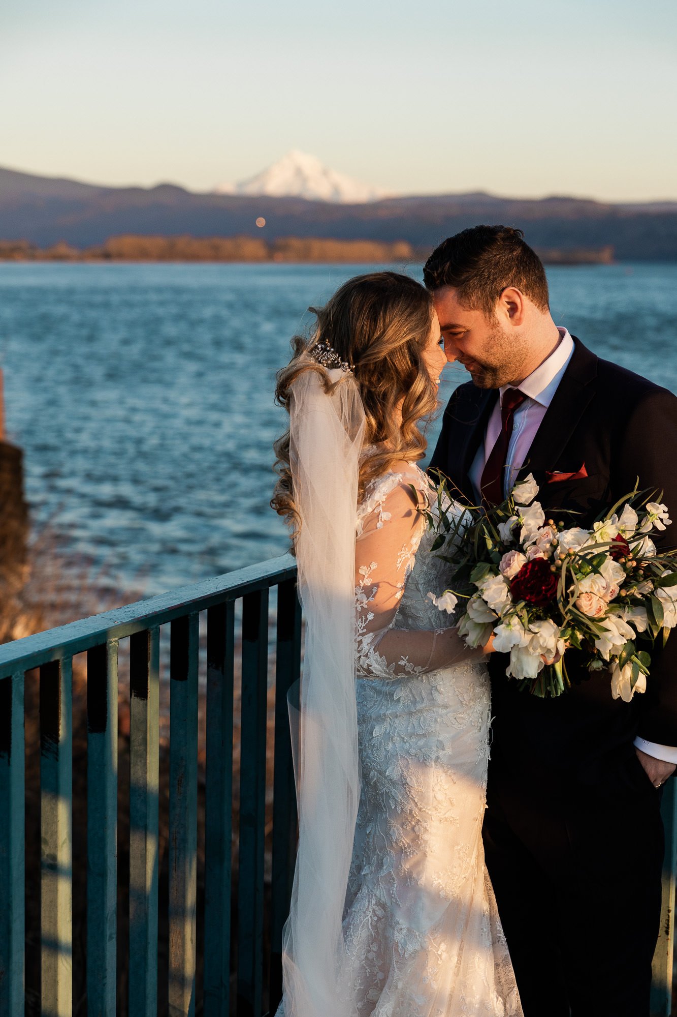 bride and groom face each other and smile while standing in front of columbia river