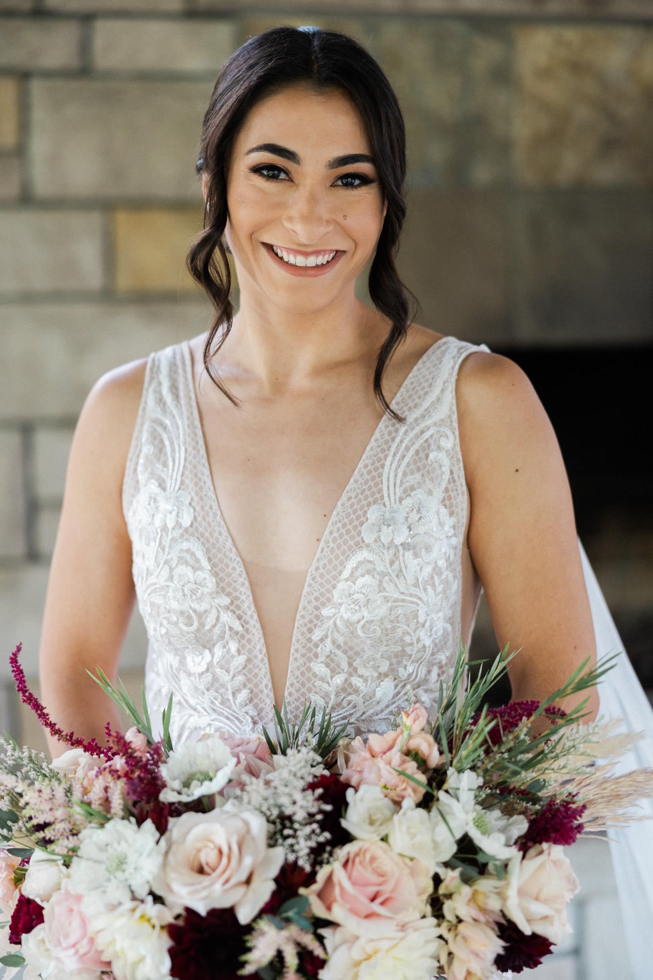 bride in white A&amp;BÉ dress holds bouquet and smiles