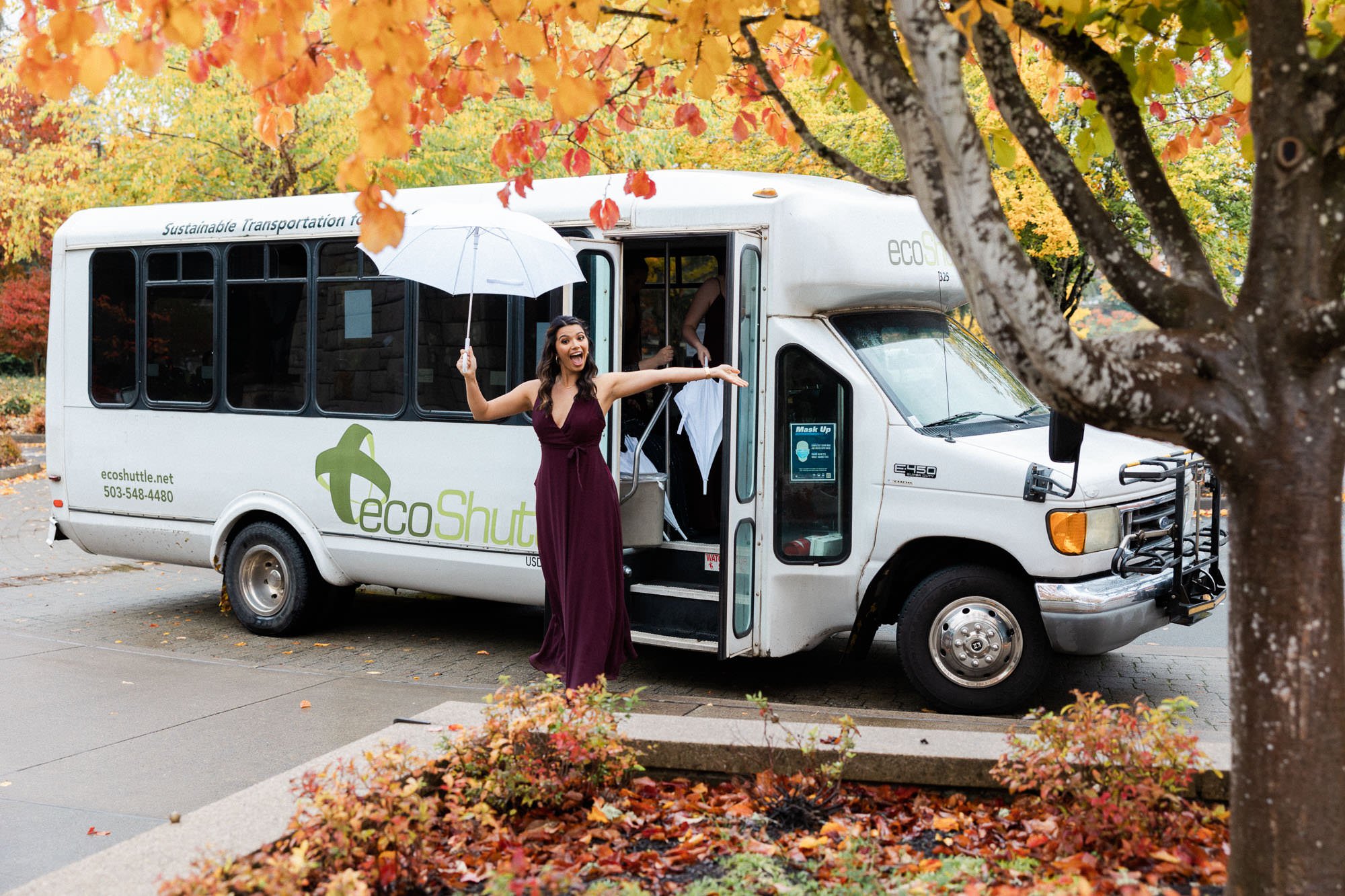 woman in burgundy dress holding white umbrella exits bus at lake oswego park