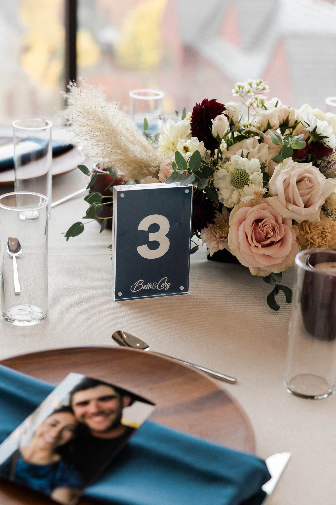 table setting at ironlight with place card, floral bouquet, water glasses, plate, and blue napkin