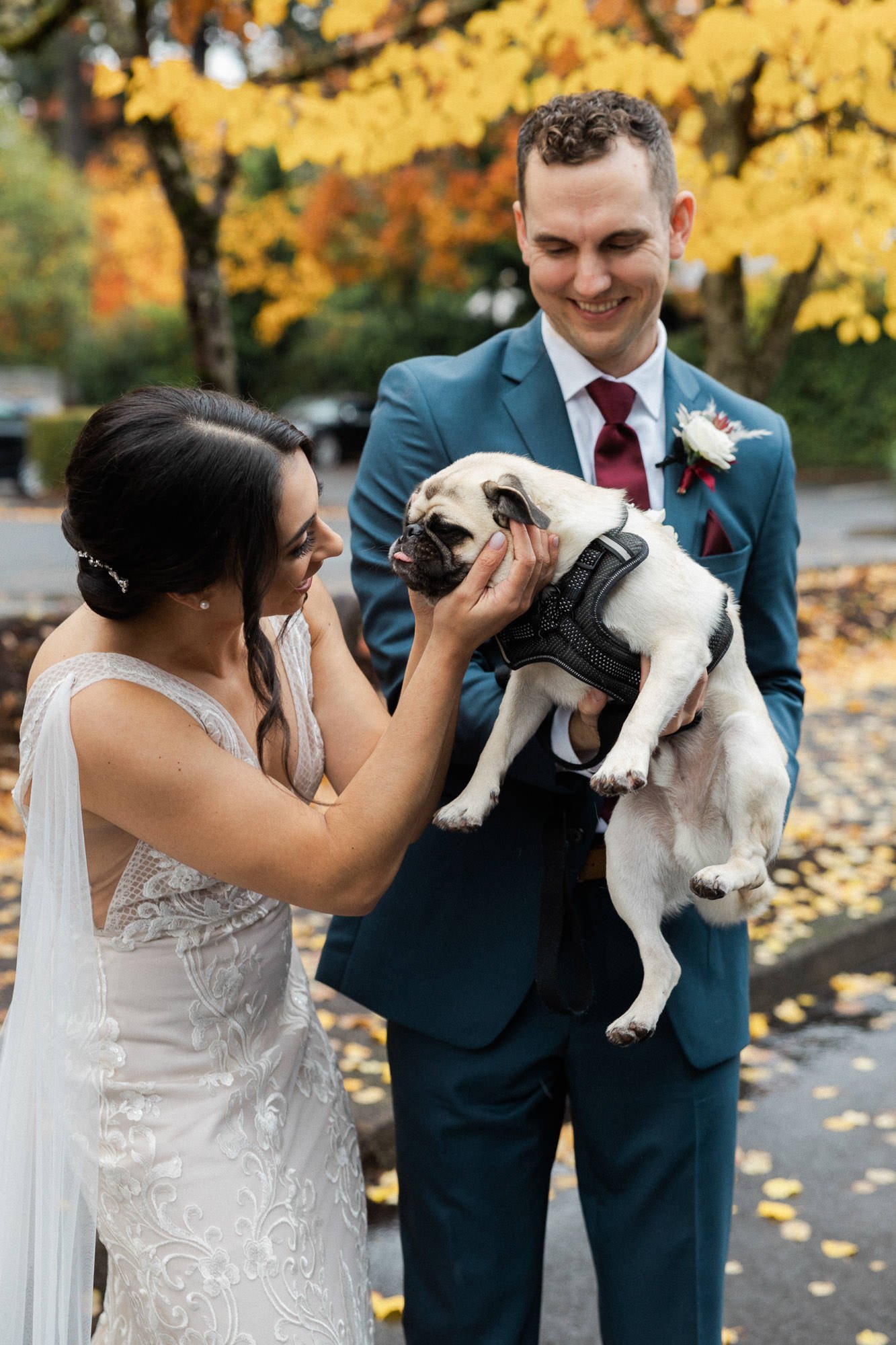 groom holds pug while bride leans in and holds pugs head with hands