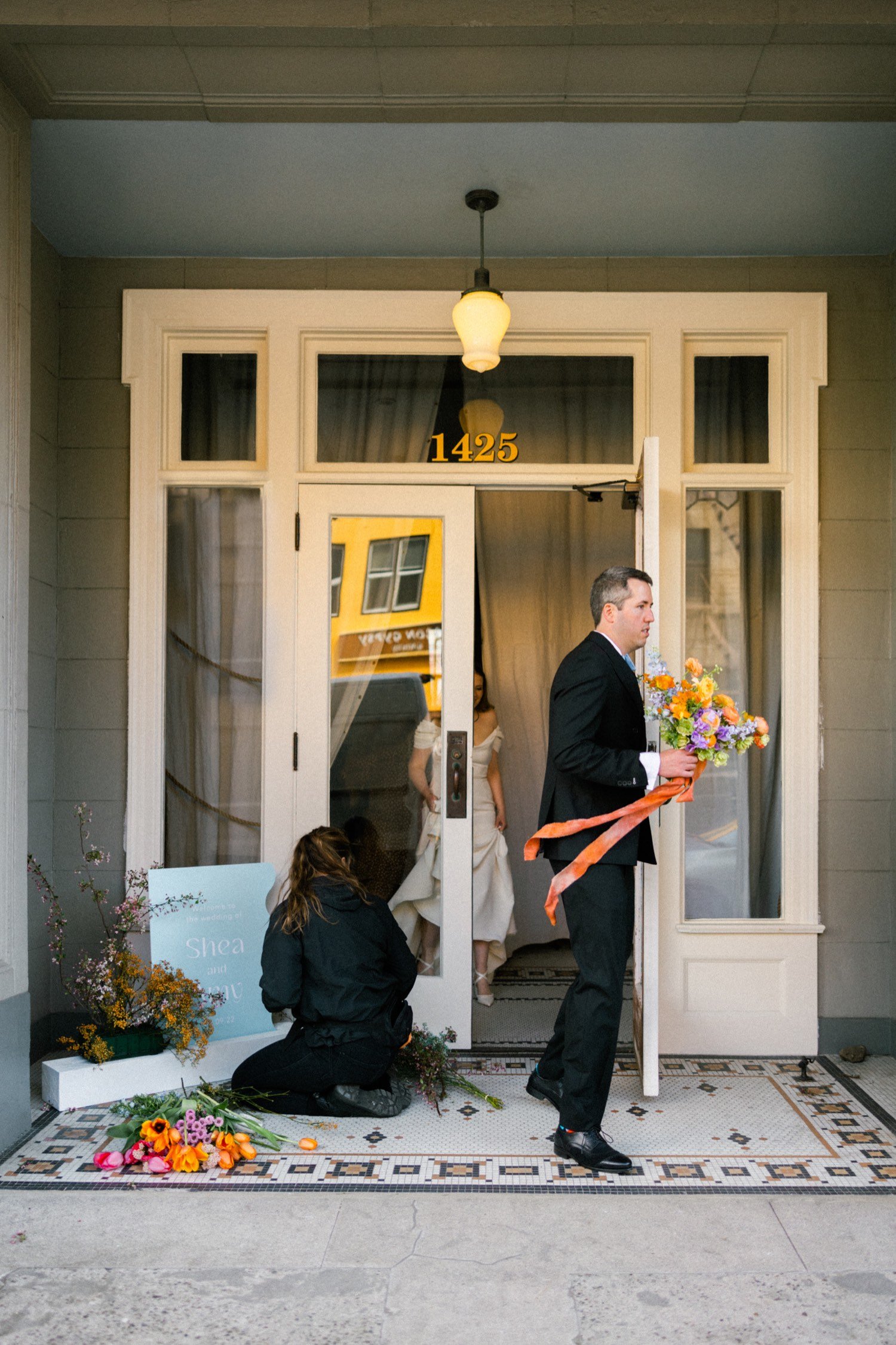 ruins at the astor astoria wedding-39_groom holding bouquet exits and holds door for bride.jpg