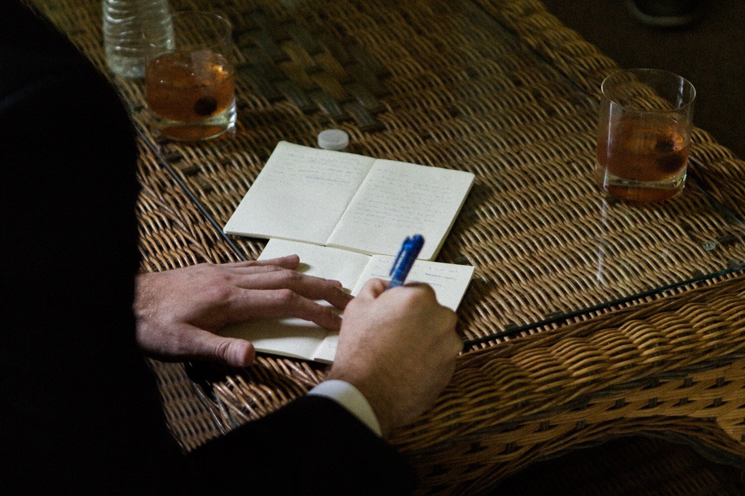 002_Mount Hood Organic Farms Wedding-9292_Man’s hand writing in small notebook next to glasses of whiskey.jpg