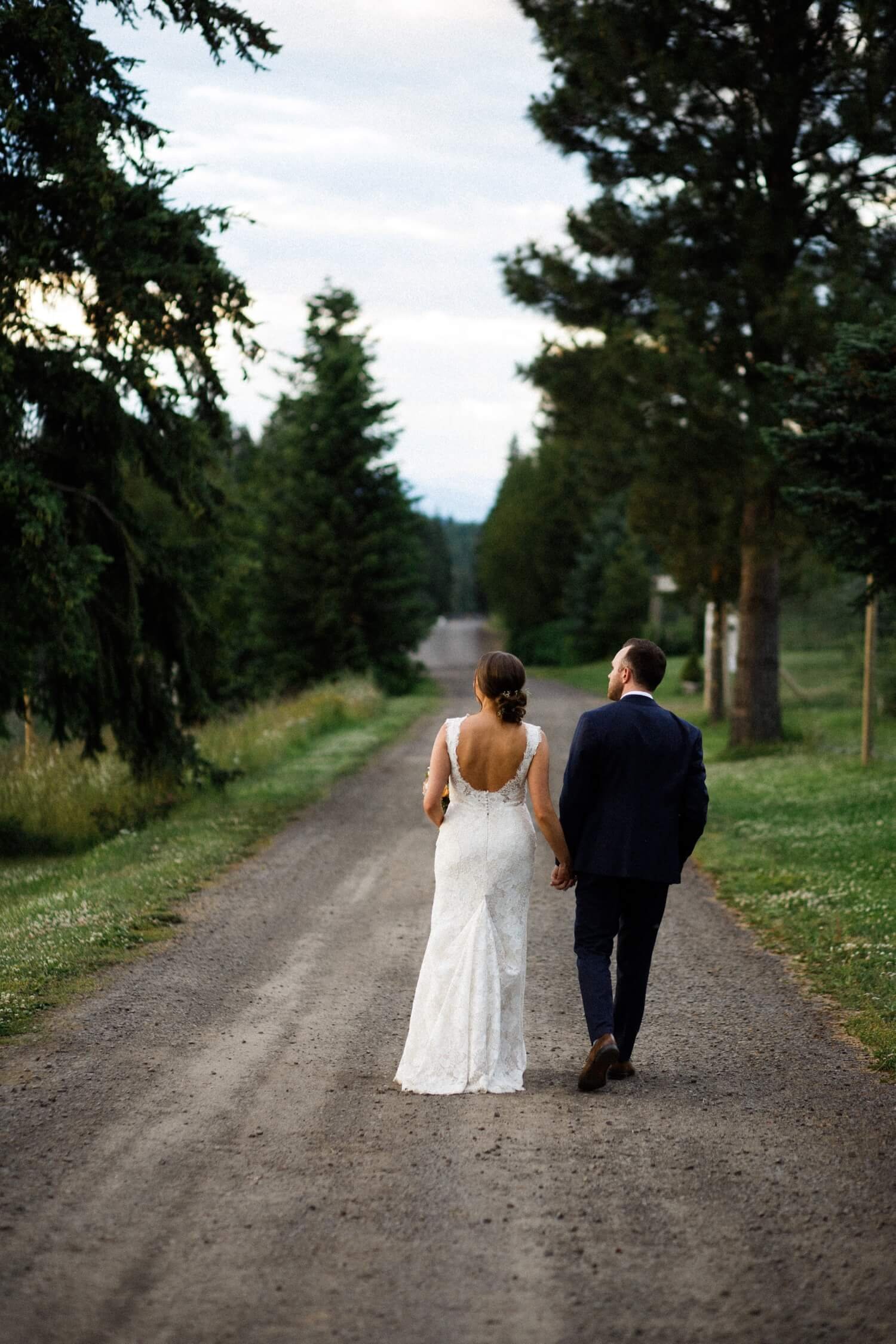 093_Mount Hood Organic Farms Wedding-Bride and groom walk hand in hand down gravel road.jpg