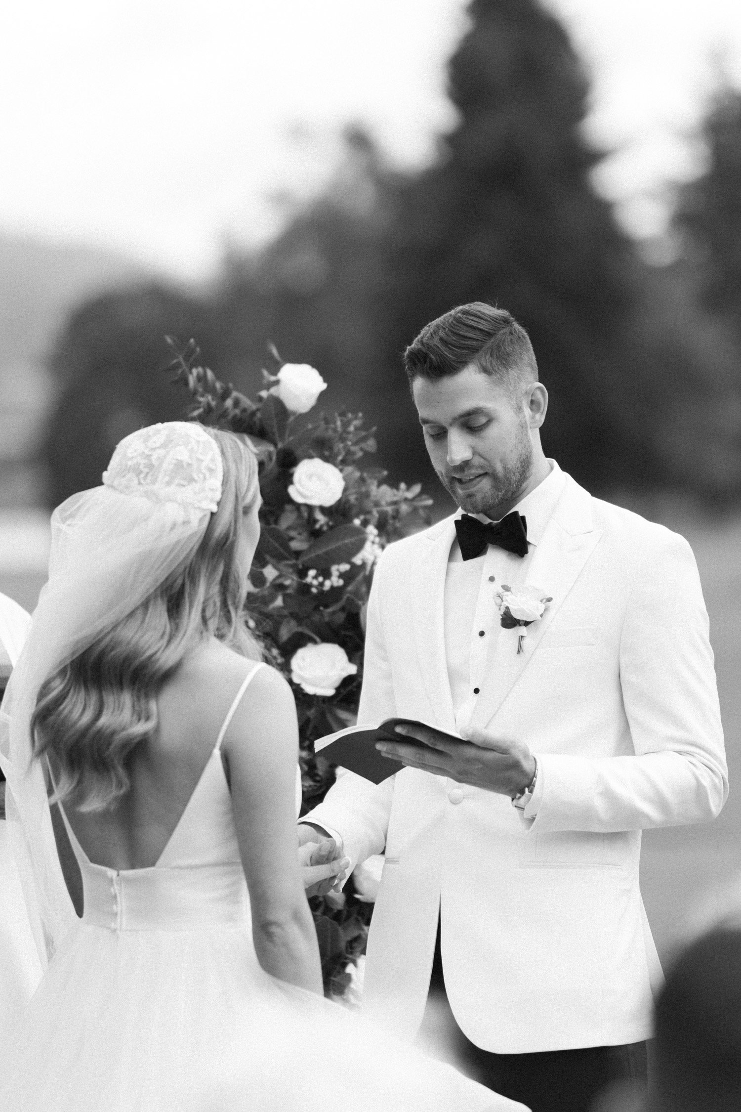  Man in white suit jacket reads wedding vows from small notebook 