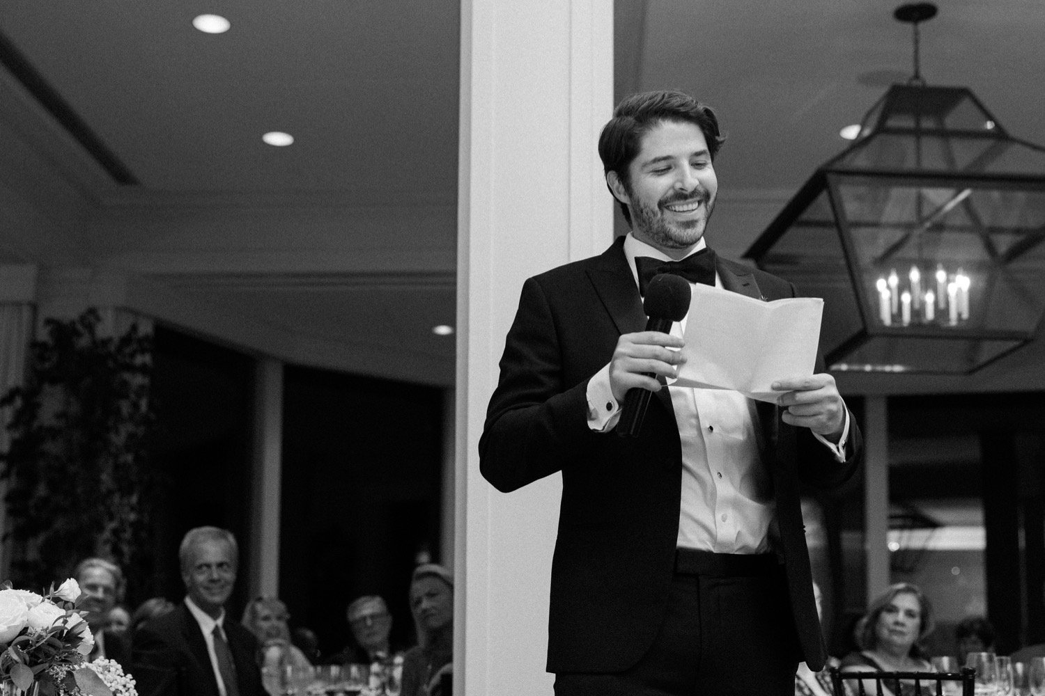  Man in black suit reads wedding toast during reception at Waverley Country Club 